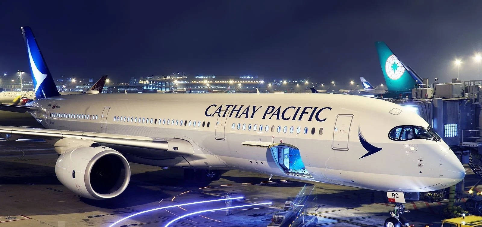 Airport 桌布 壁紙 — 一架國泰航空飛機在機場閘口夜燈下閃耀，登機梯已連接，背景中跑道燈光閃爍。