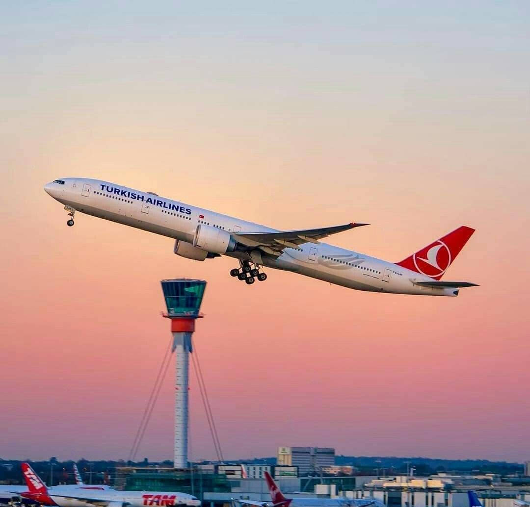 飛機 桌布 壁紙 — 一架土耳其航空噴射機在機場控制塔上方，於柔和的粉紅色和橙色日落天空中攀升。
