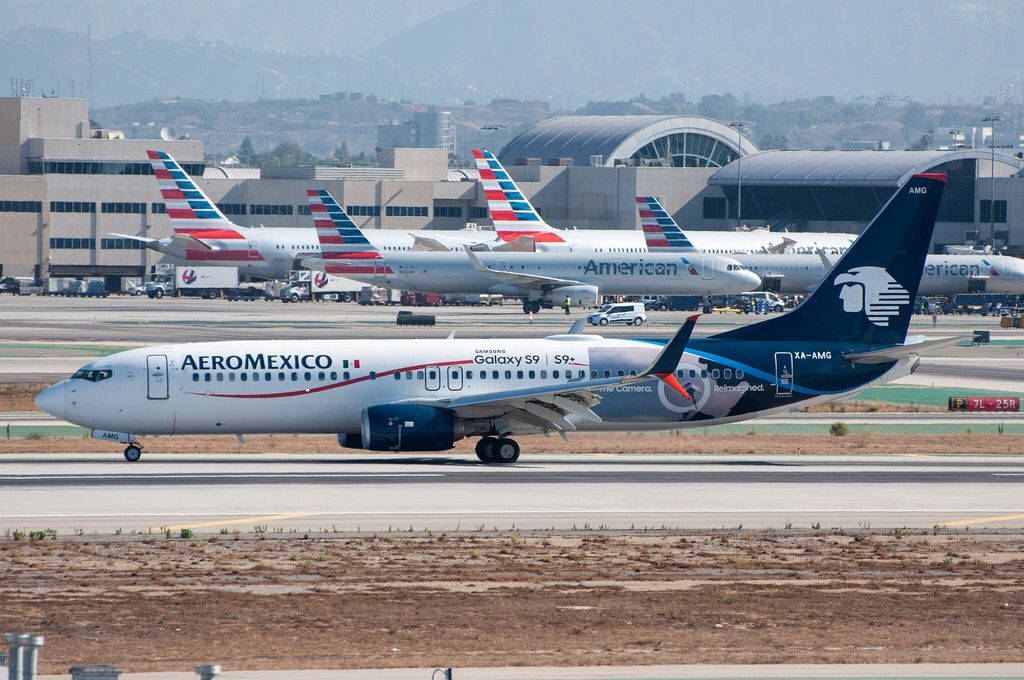 Airport 桌布 壁紙 — 一架墨西哥航空的波音737在陽光明媚的機場停機坪上滑行，背景有美國航空的噴射機和航站樓。