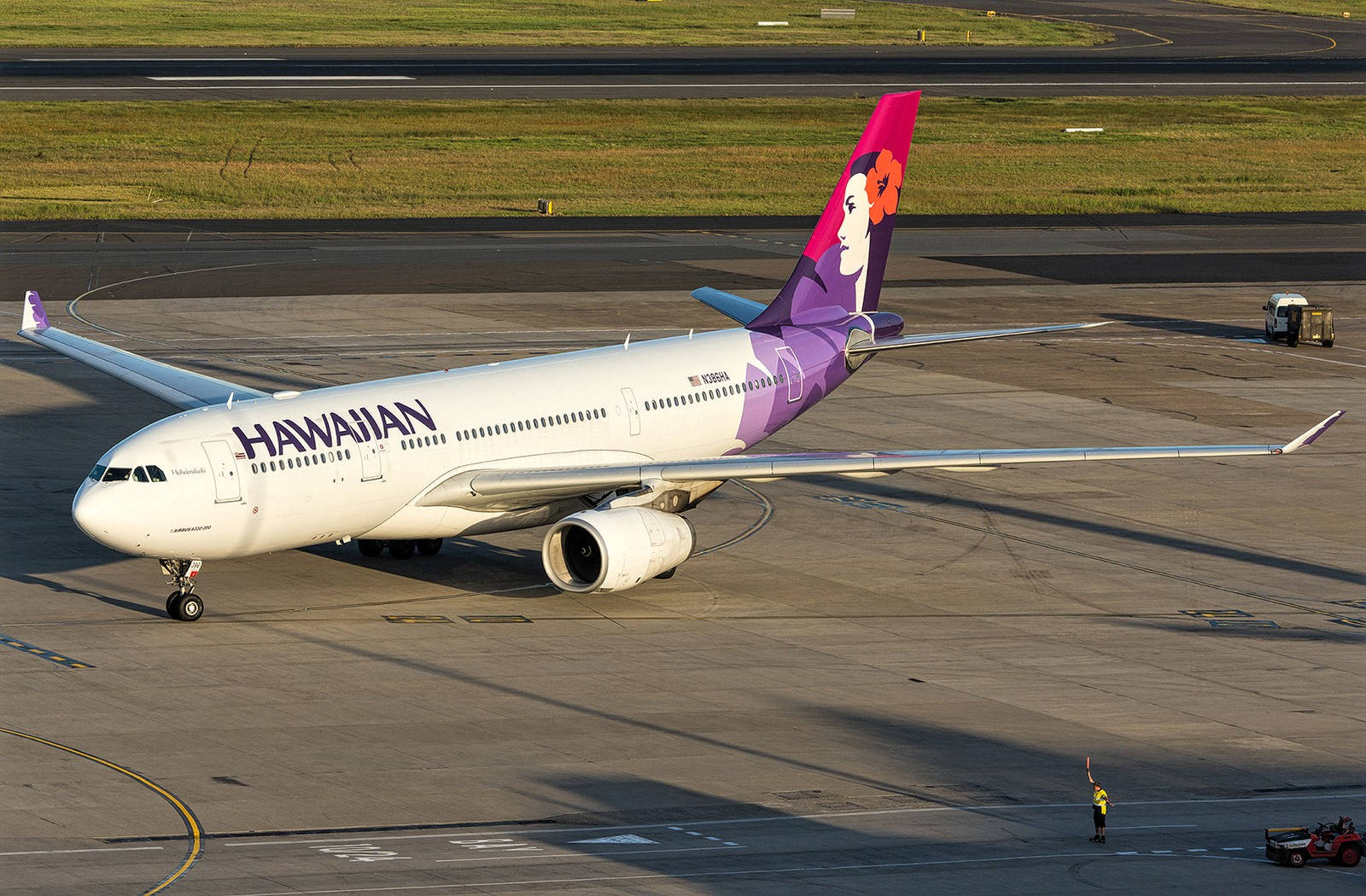 日落時，夏威夷航空飛機在停機坪上與地勤人員。