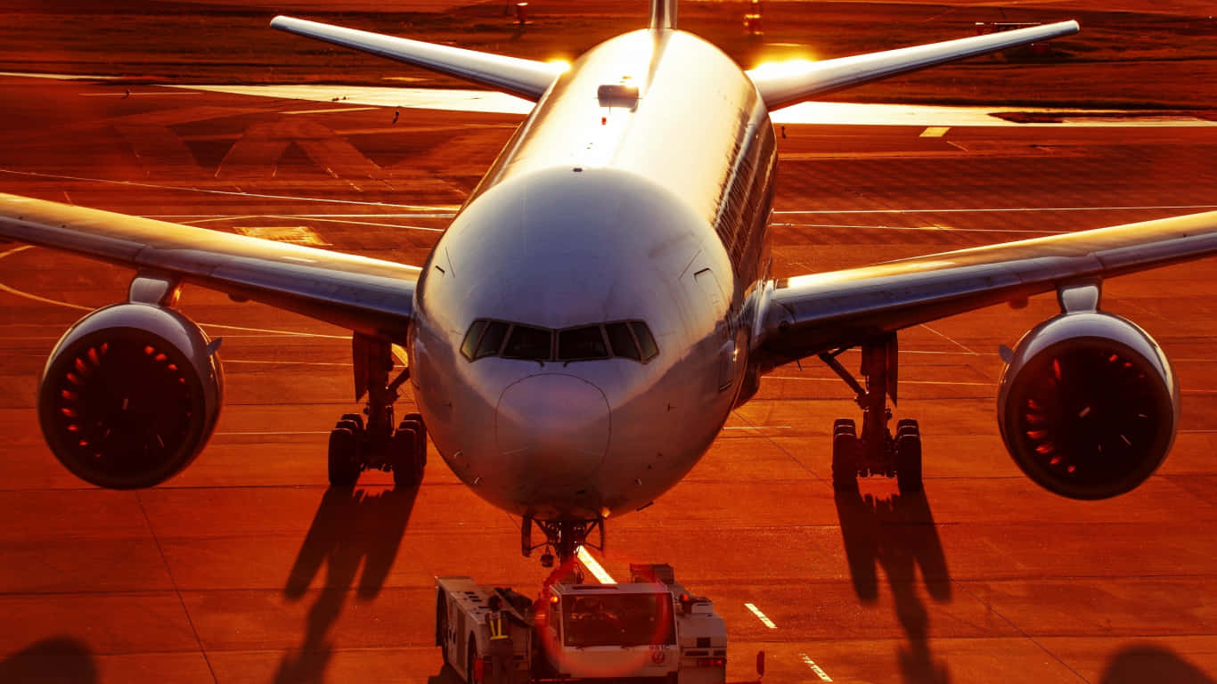  壁紙 — 一架大型客機停在停機坪上，沐浴在溫暖的金色夕陽中，引擎發光。