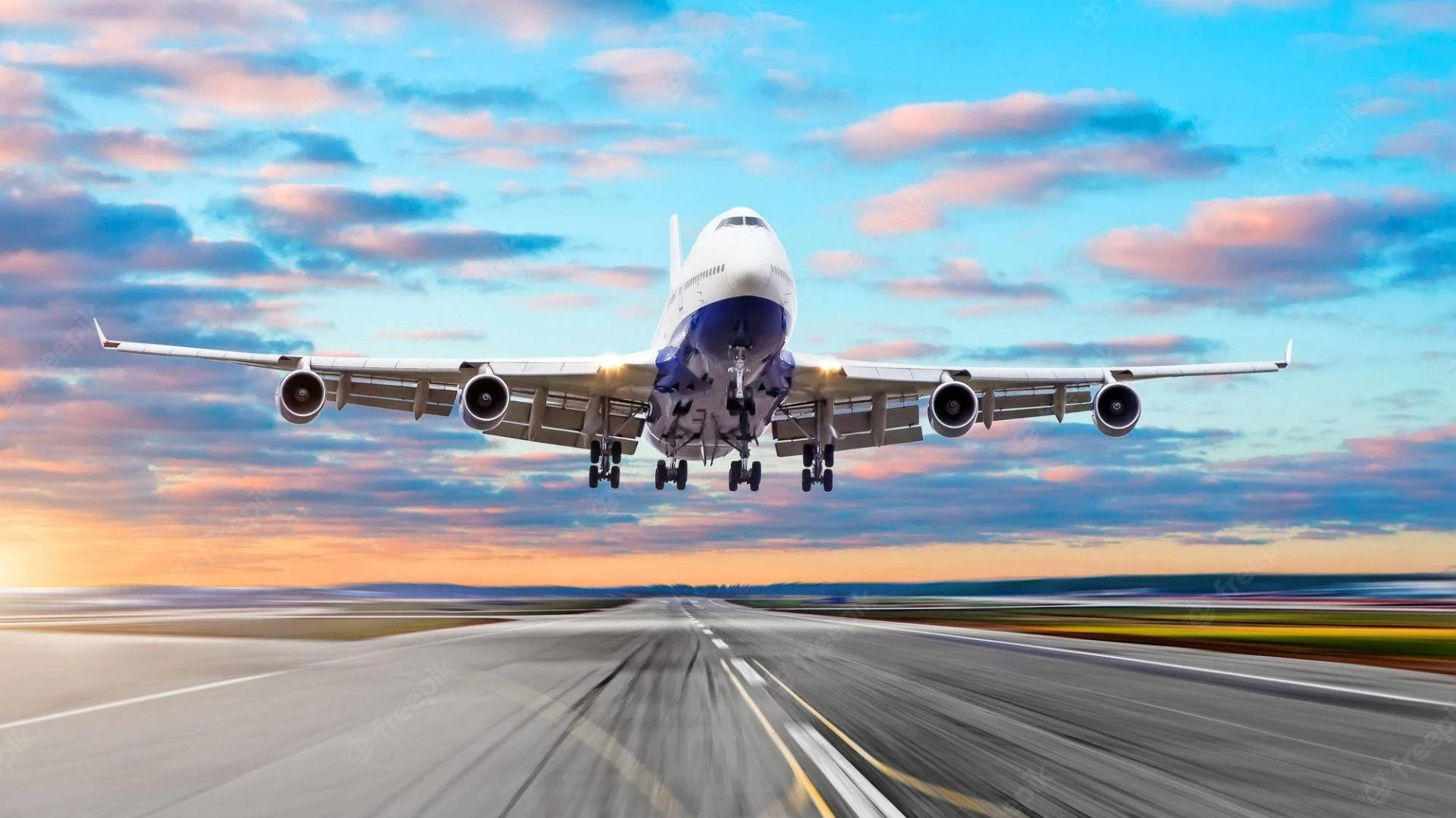 Runway 桌布 壁紙 — 一架大型客機在充滿活力的日落天空（帶有粉紅色和藍色雲彩）背景下從跑道起飛。
