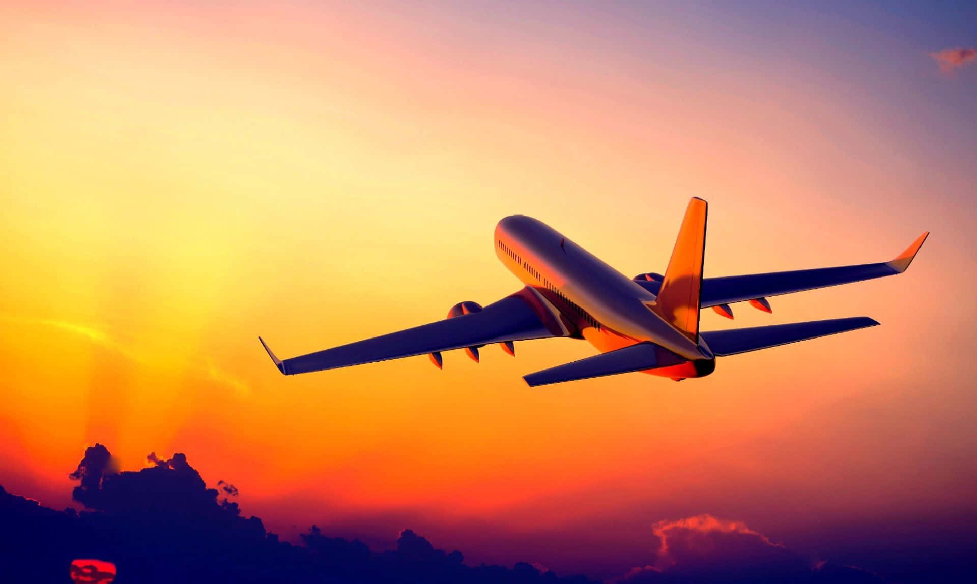 4K 飛機壁紙 桌布 壁紙 — 一架大型客機在充滿活力的日落天空中翱翔，下方有火紅的橙色和紫色雲彩。