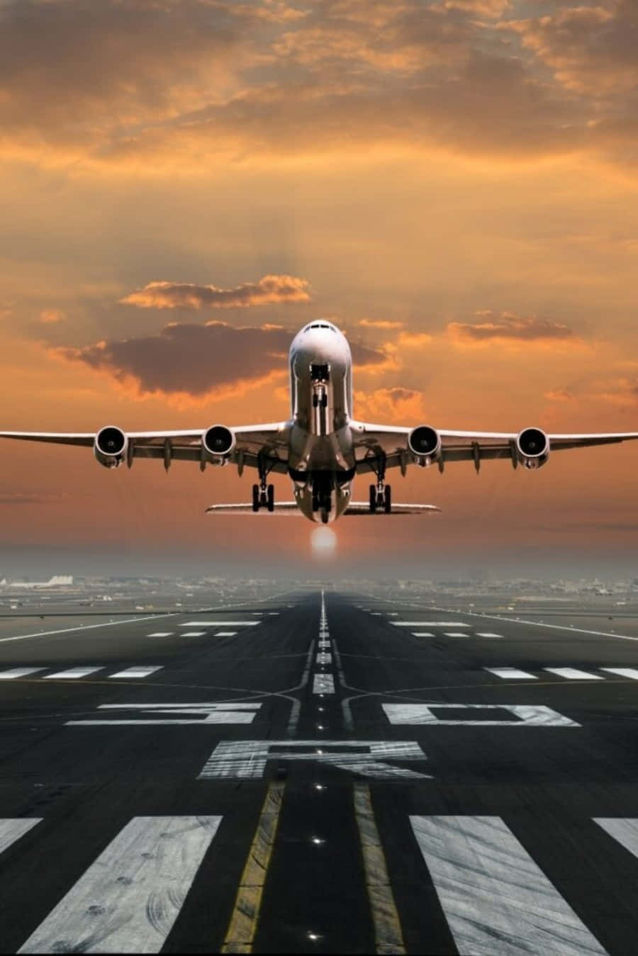 飛機 桌布 壁紙 — 一架大型客機在日落時從跑道起飛，上空有火紅的橙色雲彩。