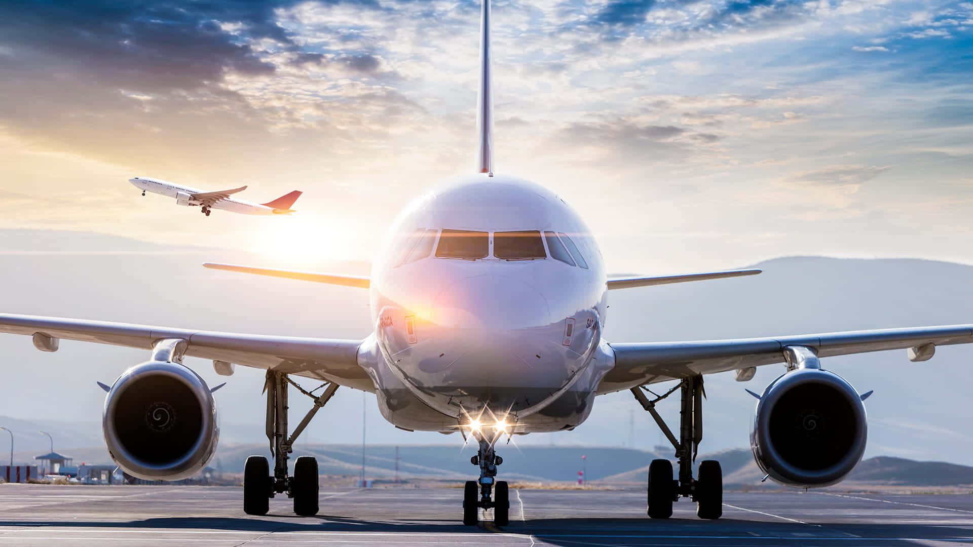 航太 桌布 壁紙 — 一架大型客機在跑道上面向鏡頭，夕陽在其後方落下，灑下金色光芒，另一架飛機在上空飛過。