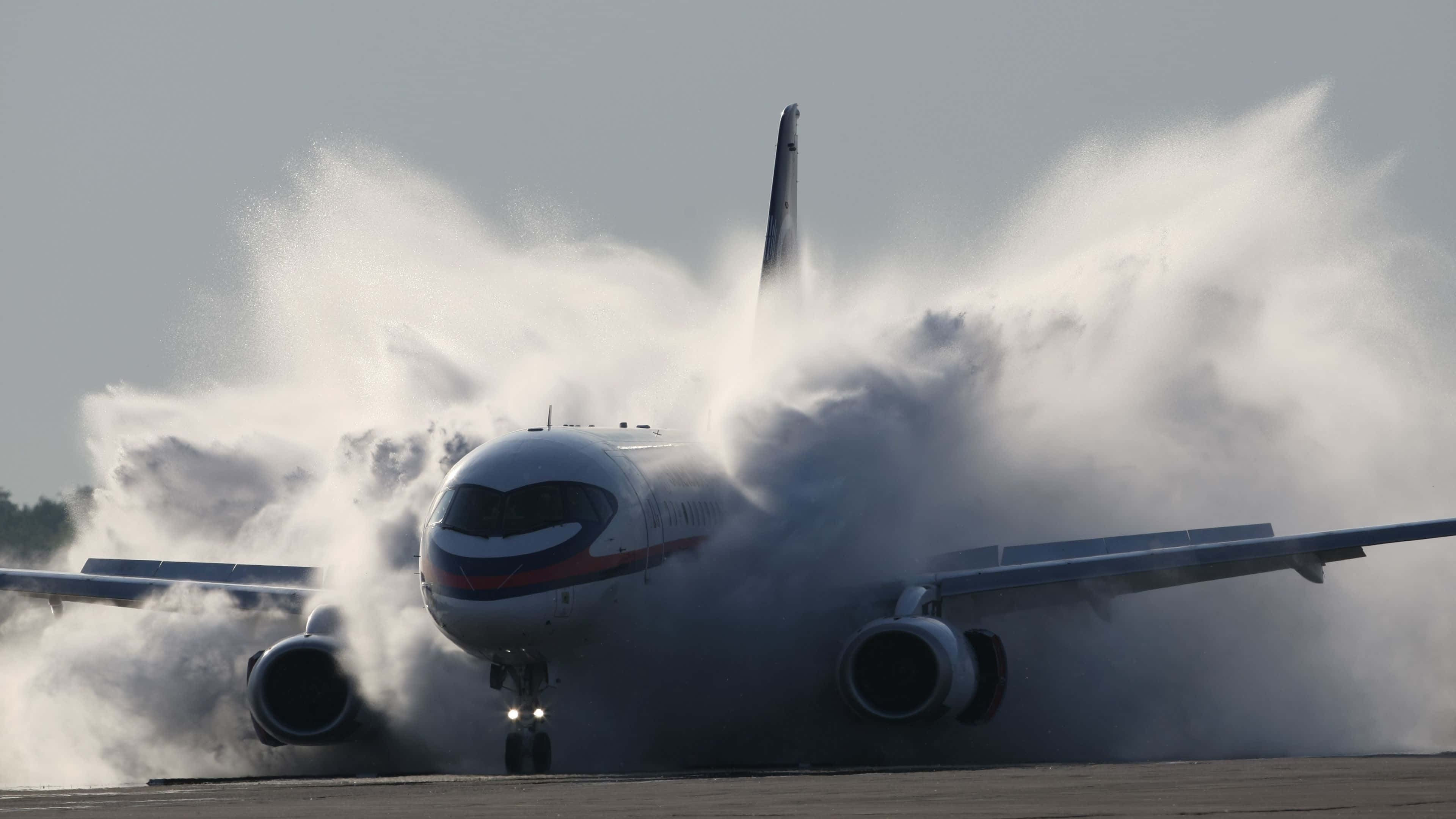 Plane 桌布 壁紙 — 一架大型客機在高速滑行時衝過跑道上的厚厚水霧雲。