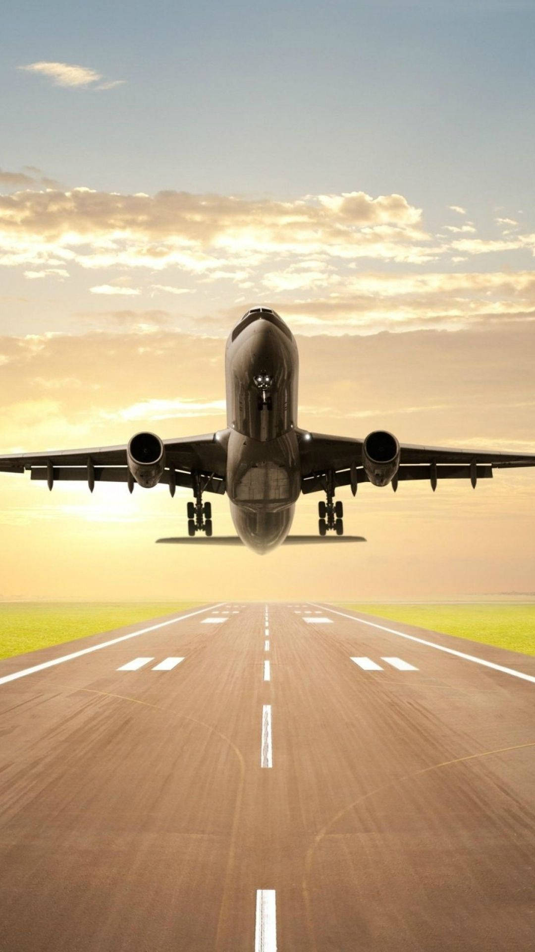 飛機 桌布 壁紙 — 一架大型客機從沐浴在金色日落光線中的跑道上升，上方有散落的雲朵。