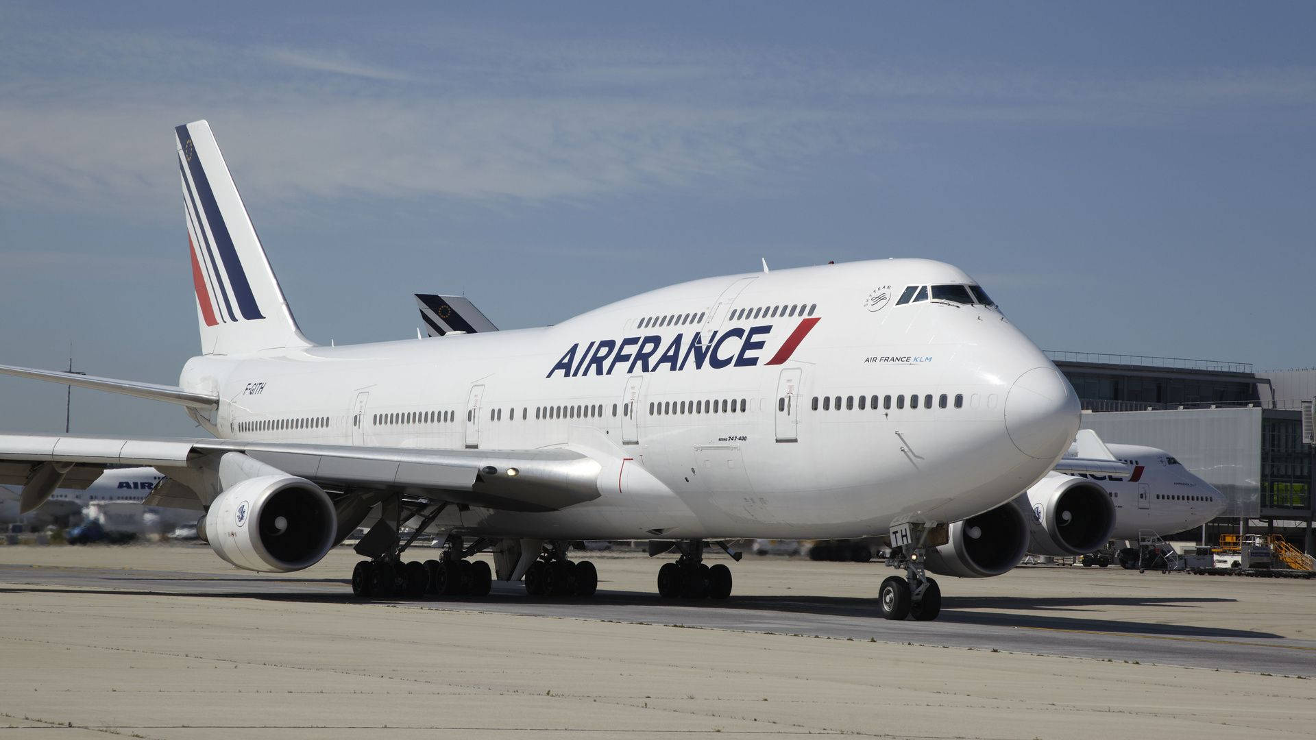 Plane 桌布 壁紙 — 一架大型白色法國航空波音747停放在陽光明媚的機場停機坪上，天空清澈湛藍，遠處有機庫。