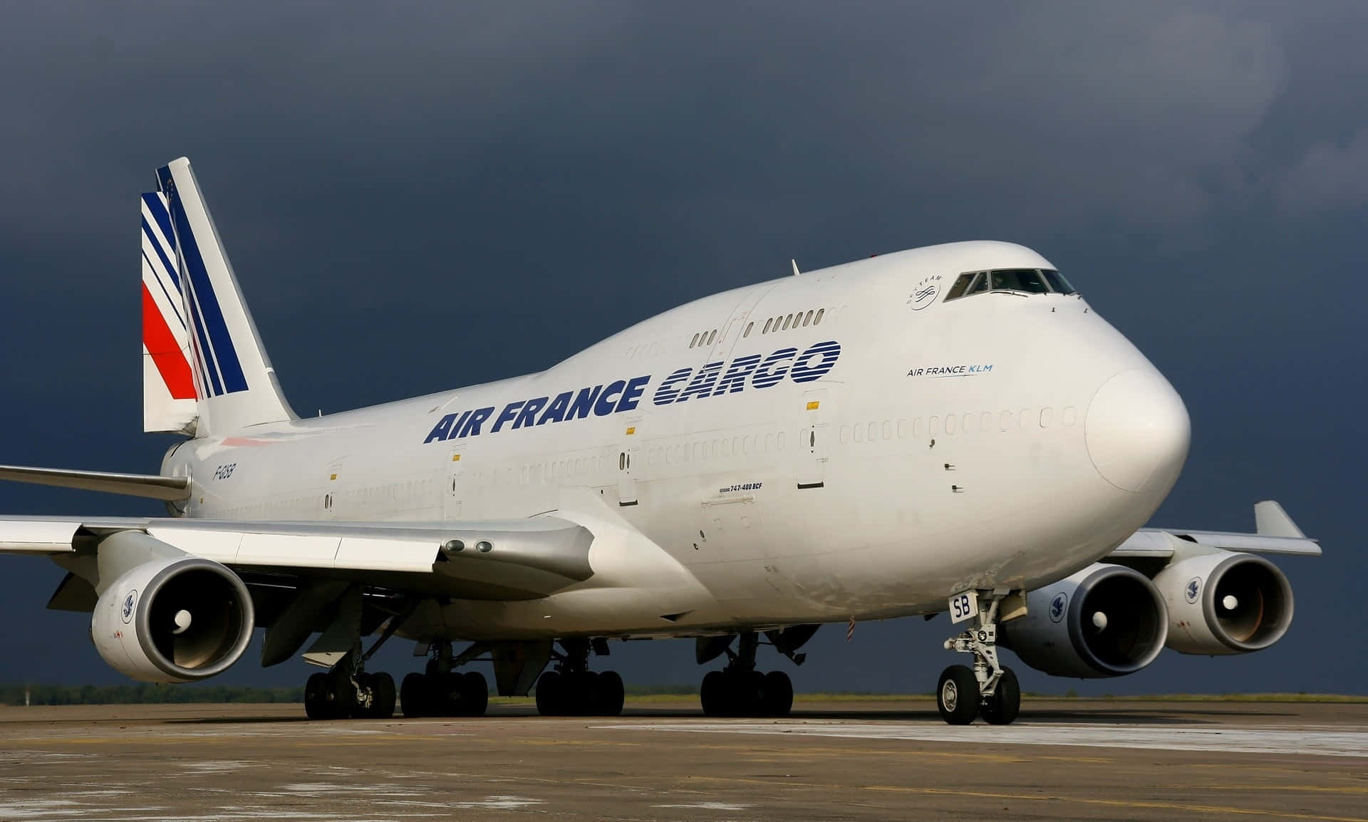 Jumbo Jets 桌布 壁紙 — 一架大型白色法國航空貨運波音747飛機在黑暗風暴天空下的跑道上。