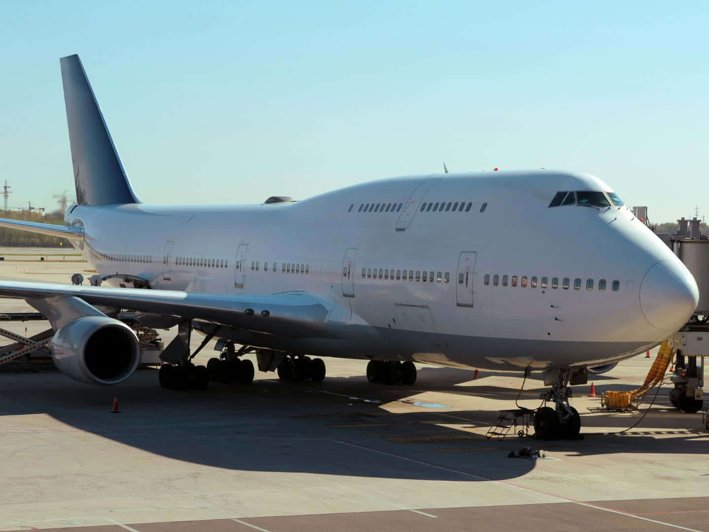 Airbus 桌布 壁紙 — 一架大型白色波音747客機停泊在陽光明媚的機場停機坪上，背景是晴朗的藍天。