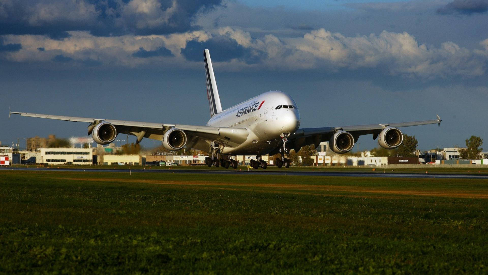 Plane 桌布 壁紙 — 一架大型白色空中巴士A380飛機在跑道上滑行，前景有綠色草地，上方多雲。