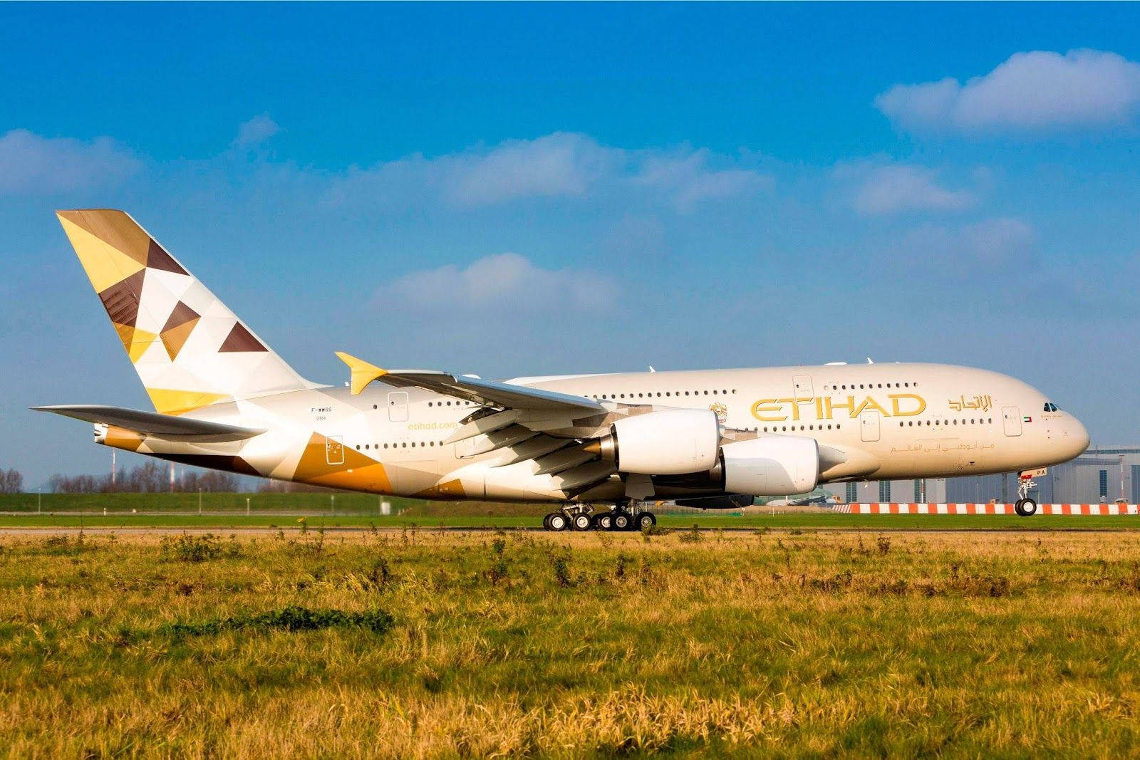 飛機 桌布 壁紙 — 一架大型阿提哈德航空空中巴士A380飛機在晴朗藍天和零星雲朵下的跑道上滑行。