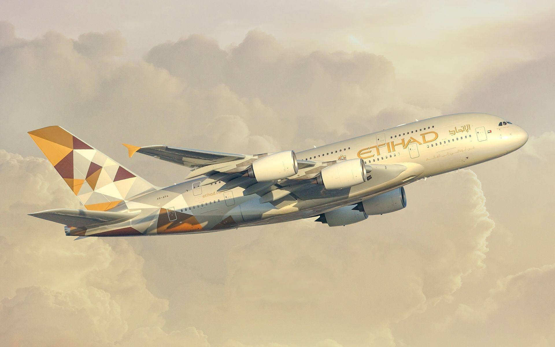 flying 桌布 壁紙 — 一架大型阿提哈德航空空中巴士A380在日落時優雅地翱翔於柔軟的金色雲層中。