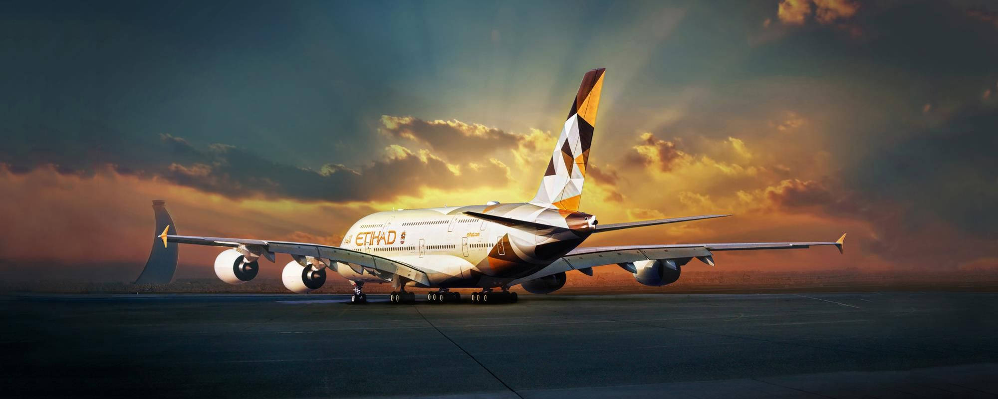 Airport 桌布 壁紙 — 一架大型阿聯酋航空空中巴士A380飛機停在跑道上，背景是壯麗的日落天空，金色雲彩。