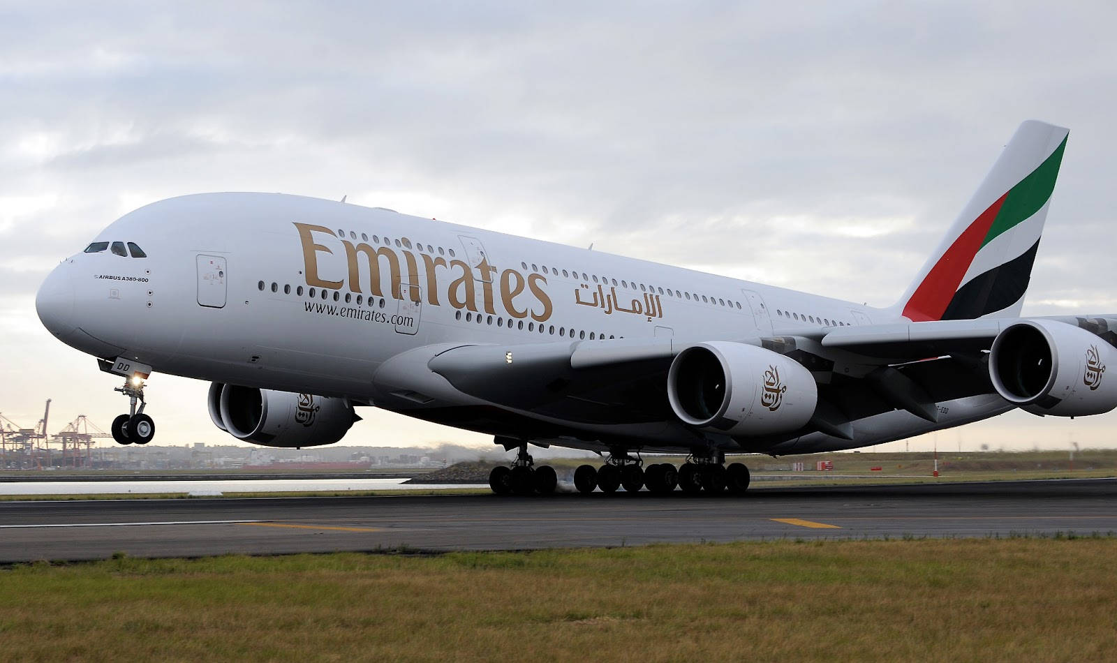 Airport 桌布 壁紙 — 一架大型阿聯酋航空空中巴士A380飛機在陰天下滑行，遠處可見工業起重機。