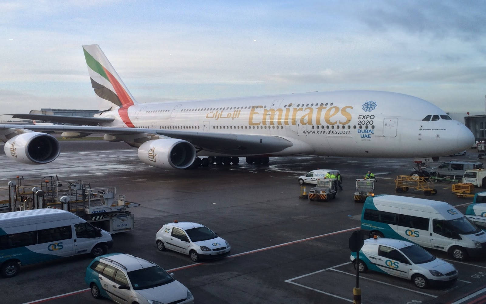 阿聯酋航空A380飛機停泊在機場閘口，有地面車輛。