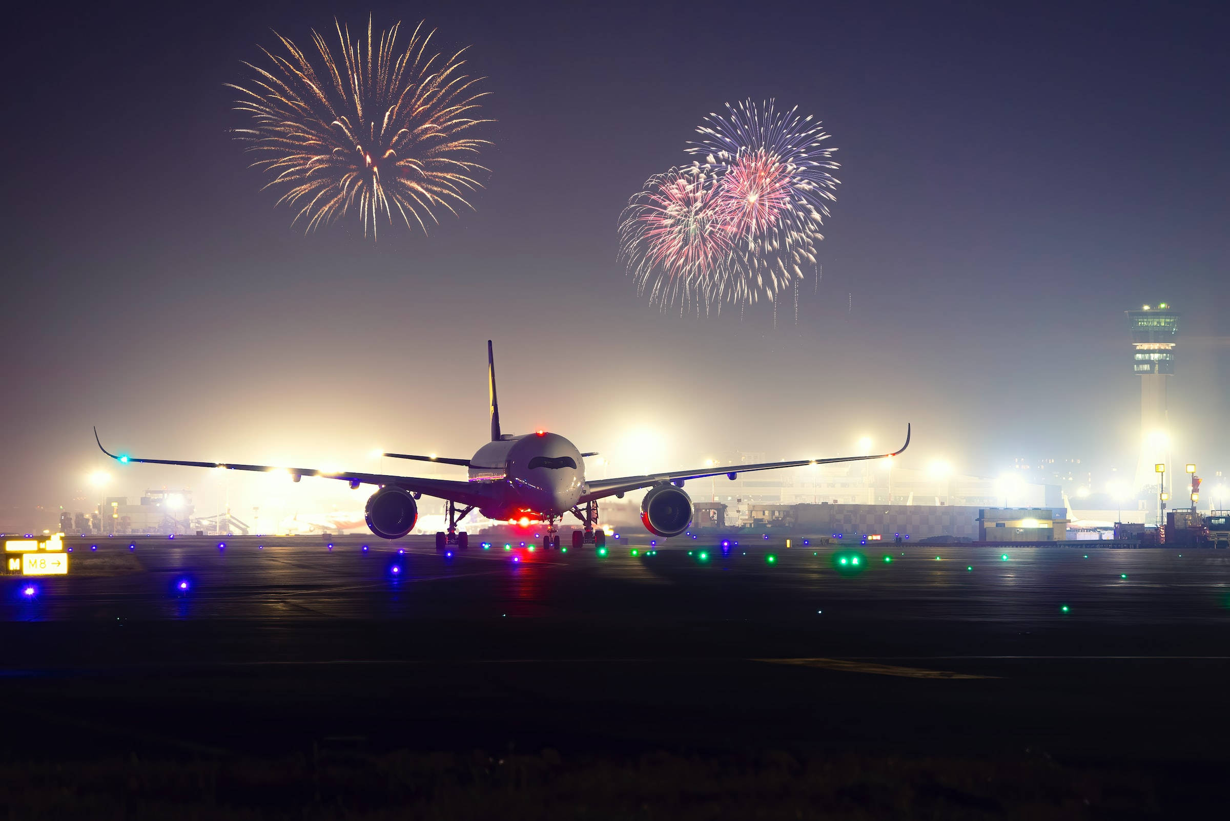 飛機 桌布 壁紙 — 一架大型飛機在夜間停在跑道上，而色彩繽紛的煙火在黑暗的天空中爆炸。