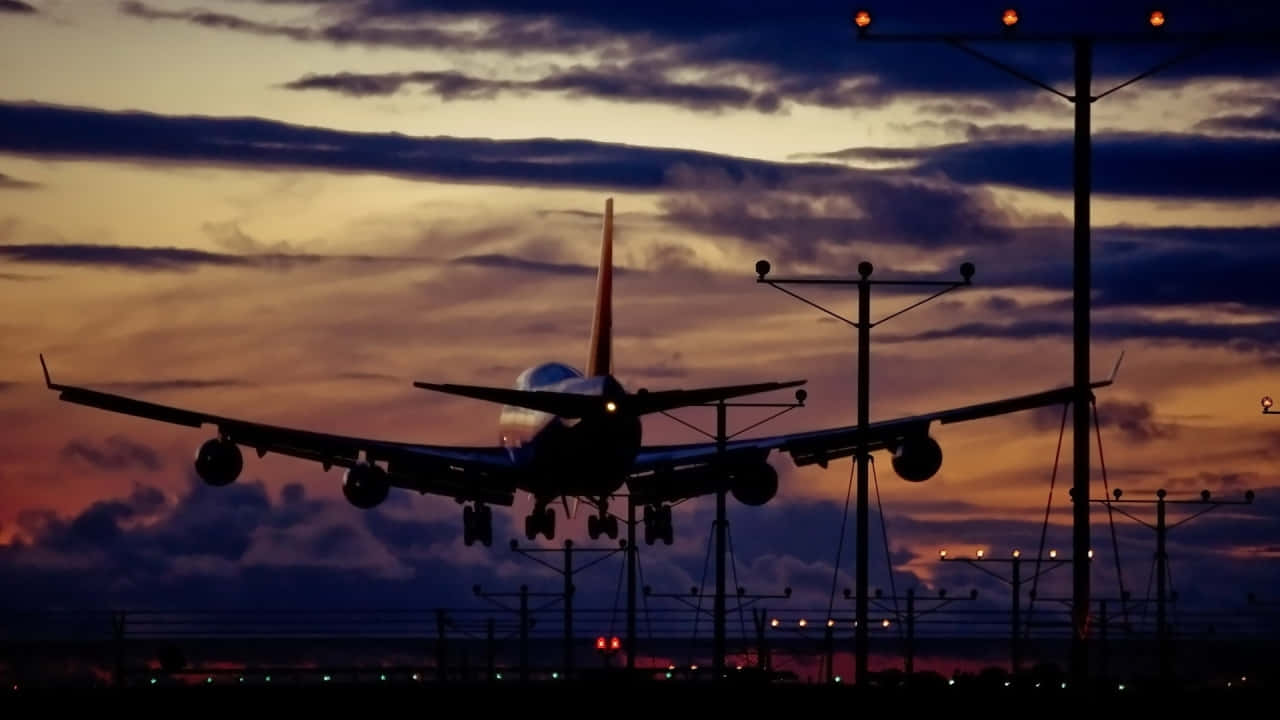 720p Plane 桌布 壁紙 — 一架大型飛機在橙紫雲彩的戲劇性暮色天空中呈現剪影。