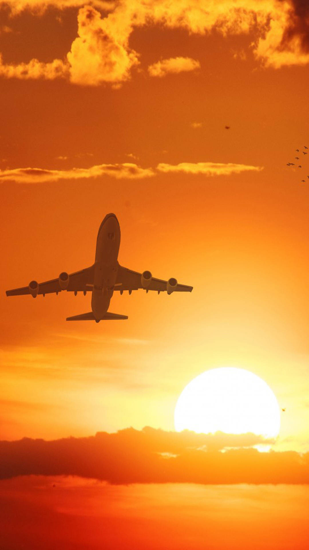 flying 桌布 壁紙 — 一架大型飛機在火紅橙色日落、明亮太陽和零星雲朵的襯托下呈現剪影。
