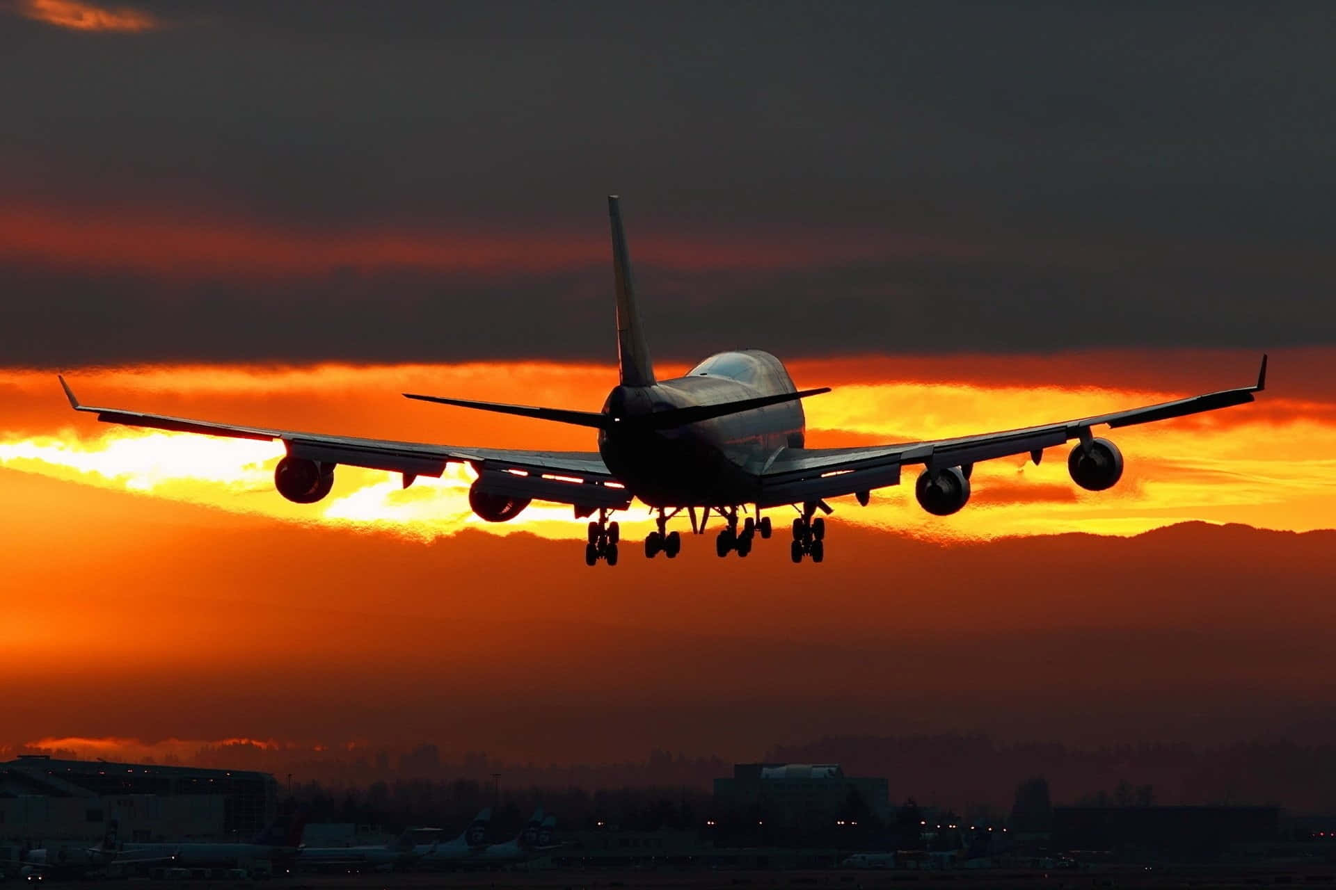 Flight 桌布 壁紙 — 一架大型飛機在降落時，以火紅的橙色夕陽為背景形成剪影。