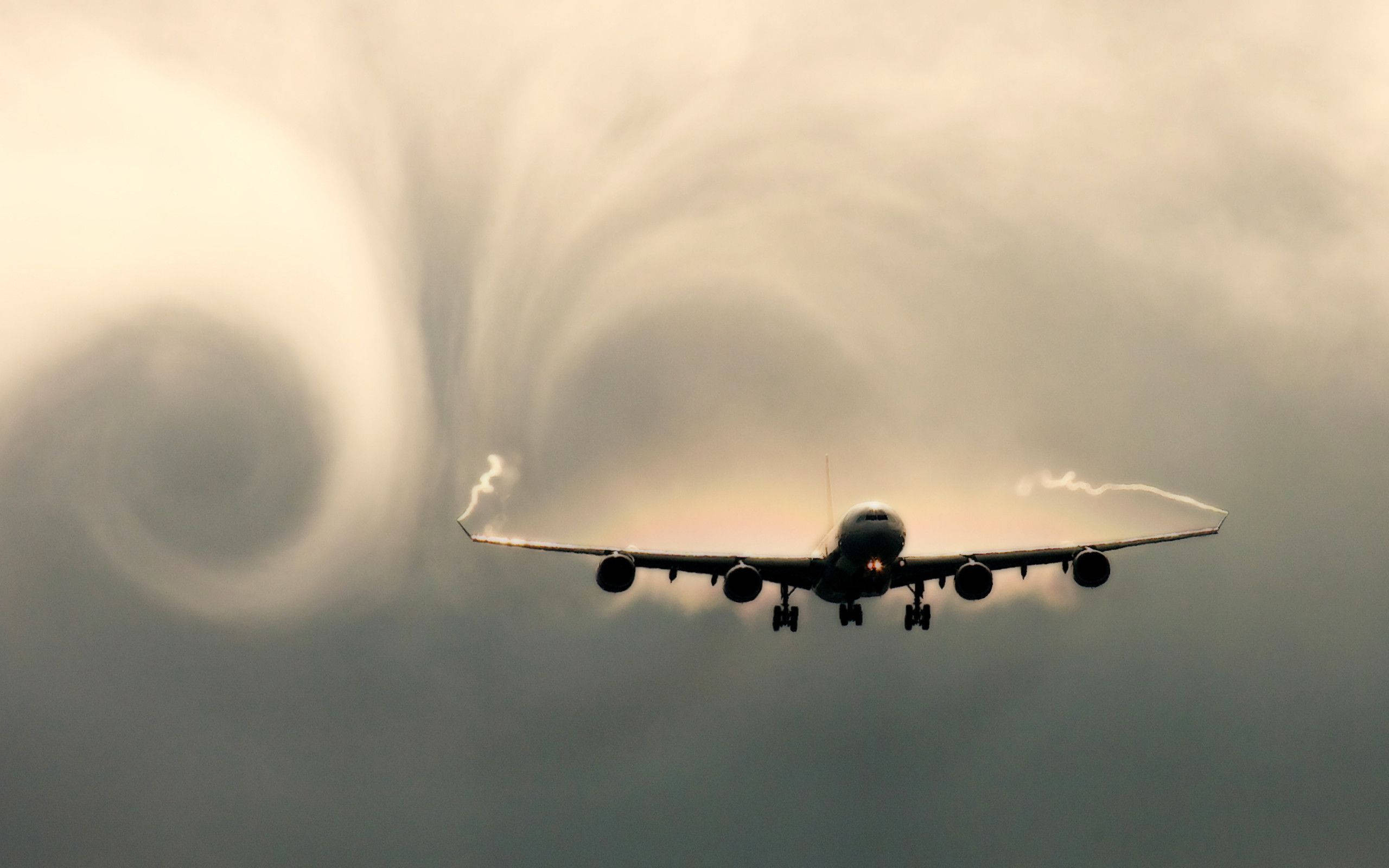 飛機 桌布 壁紙 — 一架大型飛機穿過戲劇性的雲層下降，可見的凝結尾跡映襯著陰沉天空。