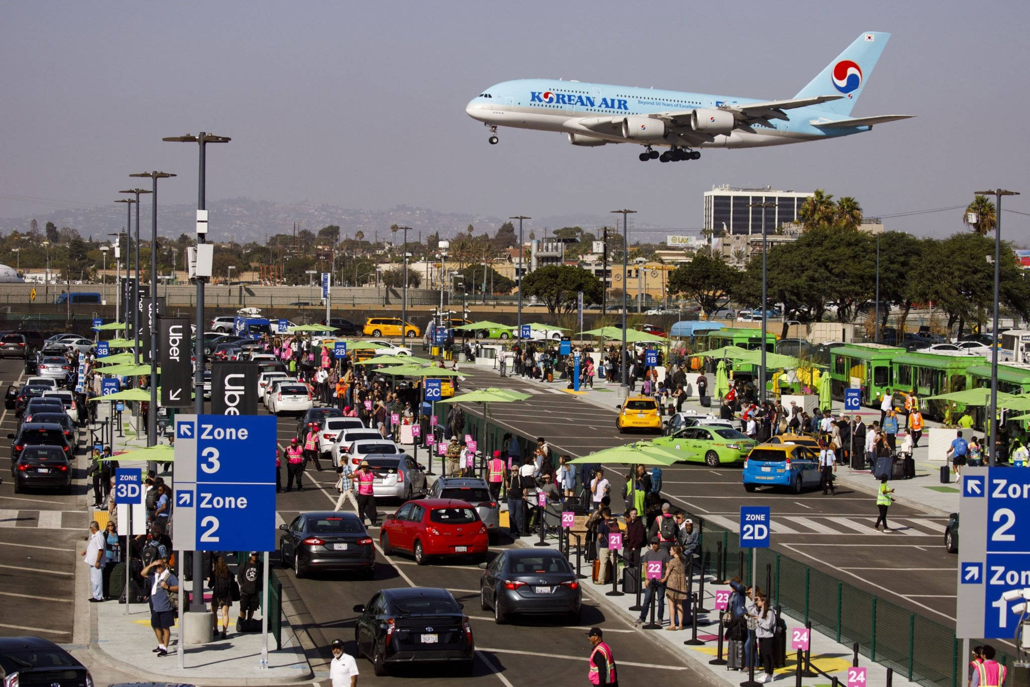 飛機 桌布 壁紙 — 一架大韓航空珍寶客機低飛越過繁忙的機場下客區，該區擠滿計程車和等候的乘客。