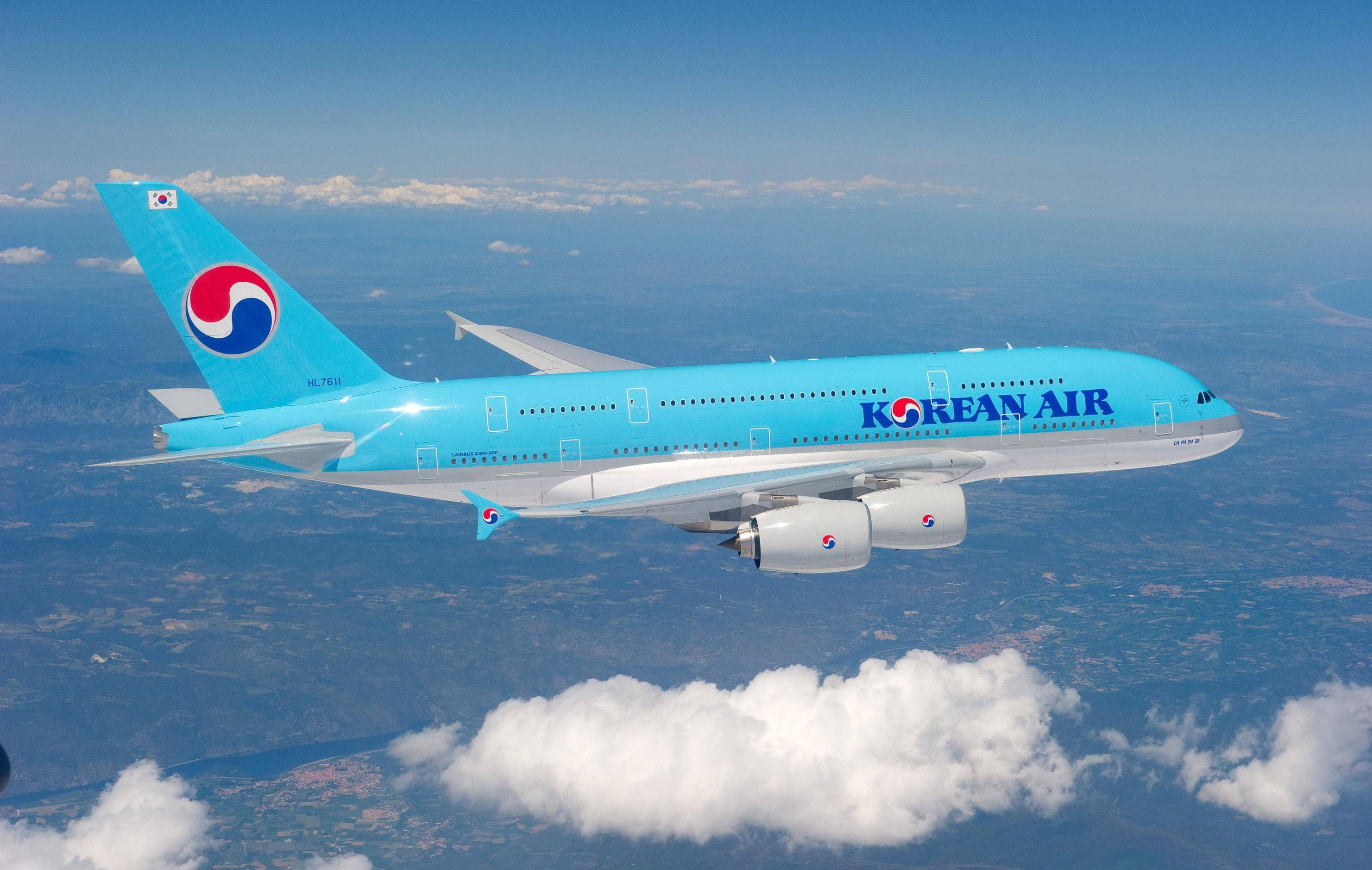 HD Plane 桌布 壁紙 — 一架大韓航空的空中巴士A380在蓬鬆的白雲之上翱翔，背景是清澈的藍天和下方的地球。