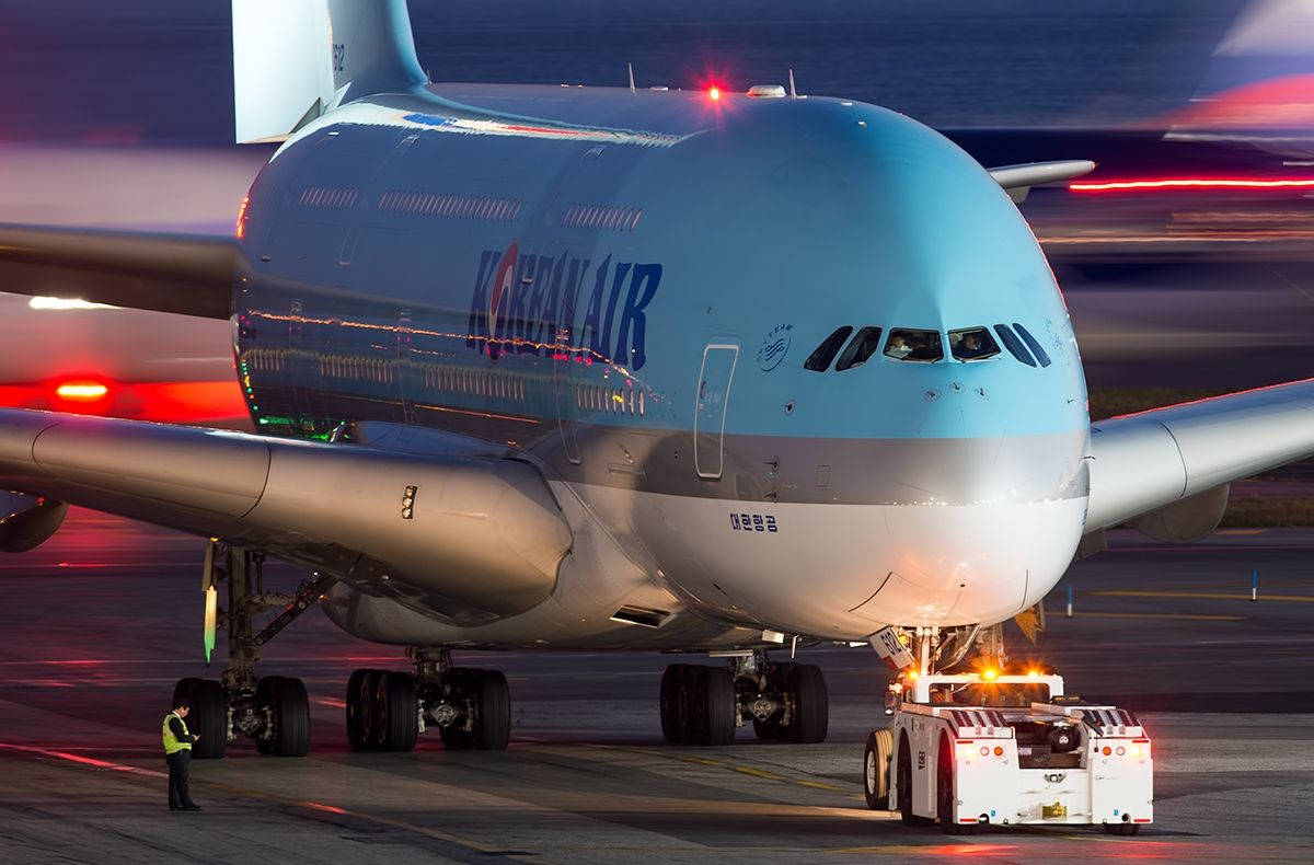 飛機 桌布 壁紙 — 一架大韓航空空中巴士A380在黃昏時被拖行，模糊的跑道燈光在後方劃過。