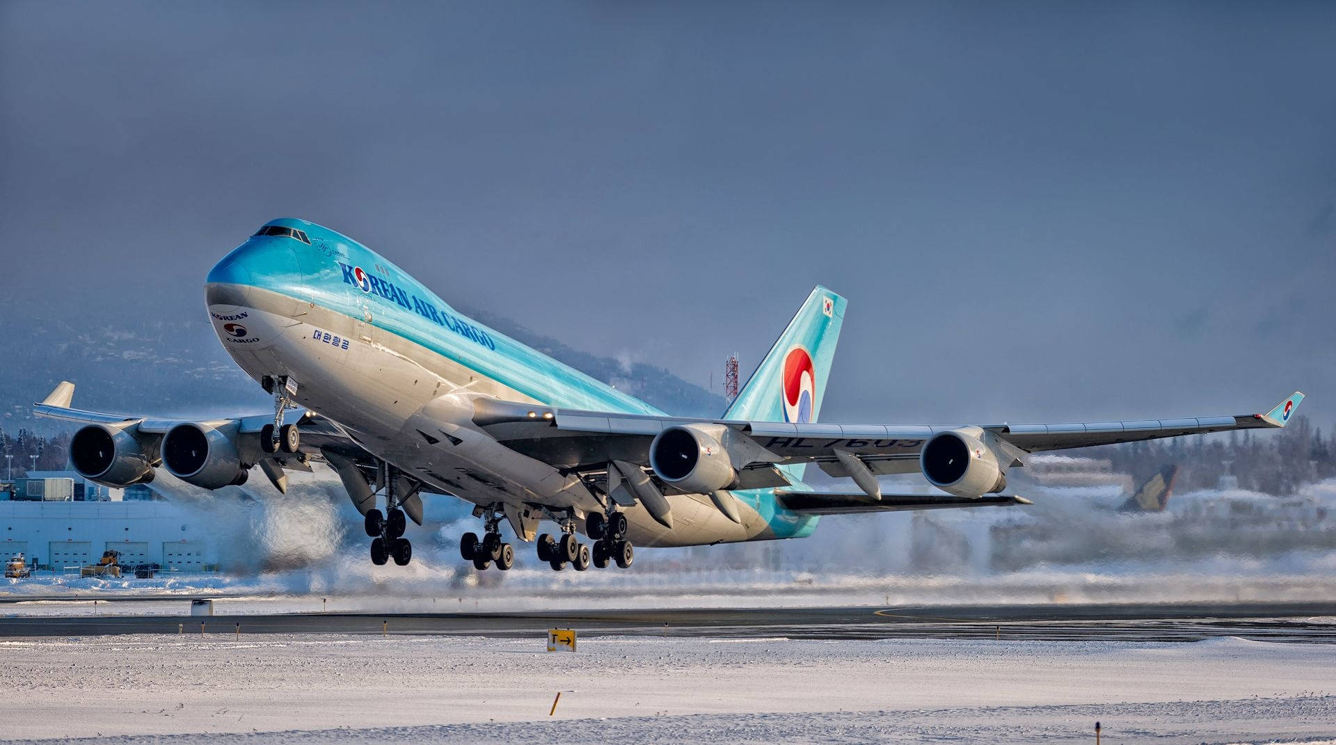 Airport 桌布 壁紙 — 一架大韓航空貨運波音747從積雪跑道起飛，背景有山脈。