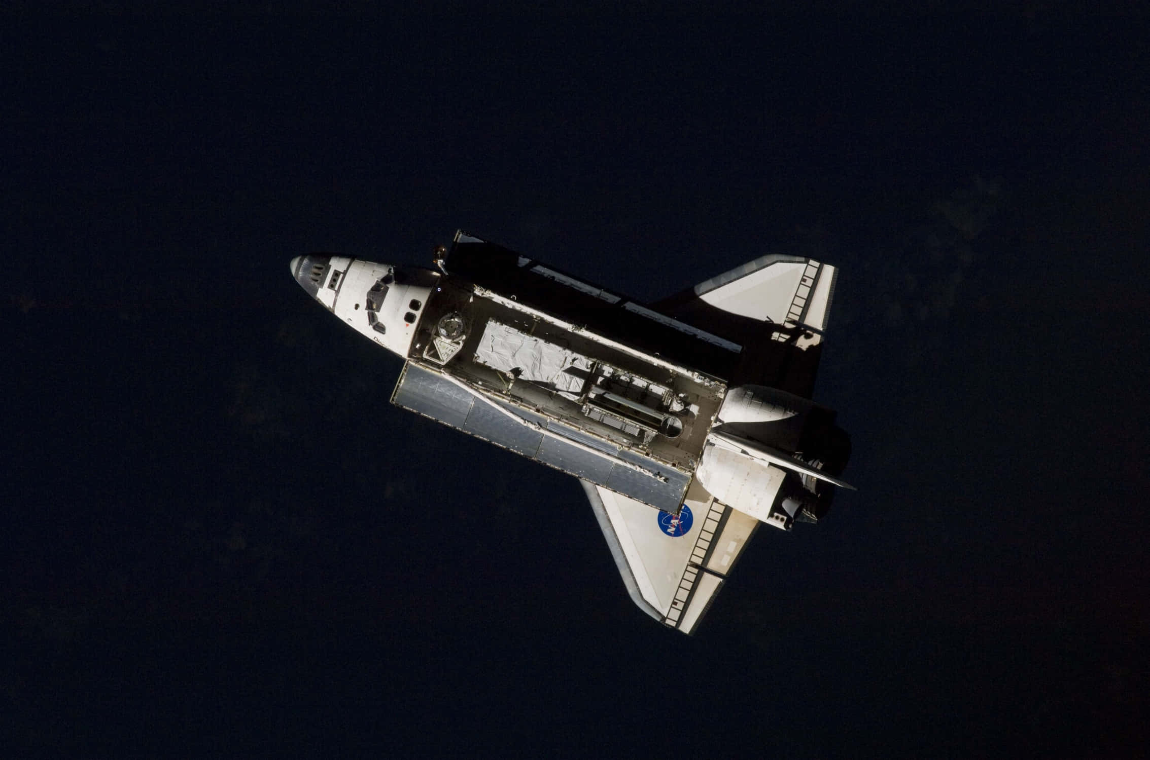 Spacecraft 桌布 壁紙 — 一架太空梭在太空的黑暗中滑行，下方可見地球彎曲的地平線。