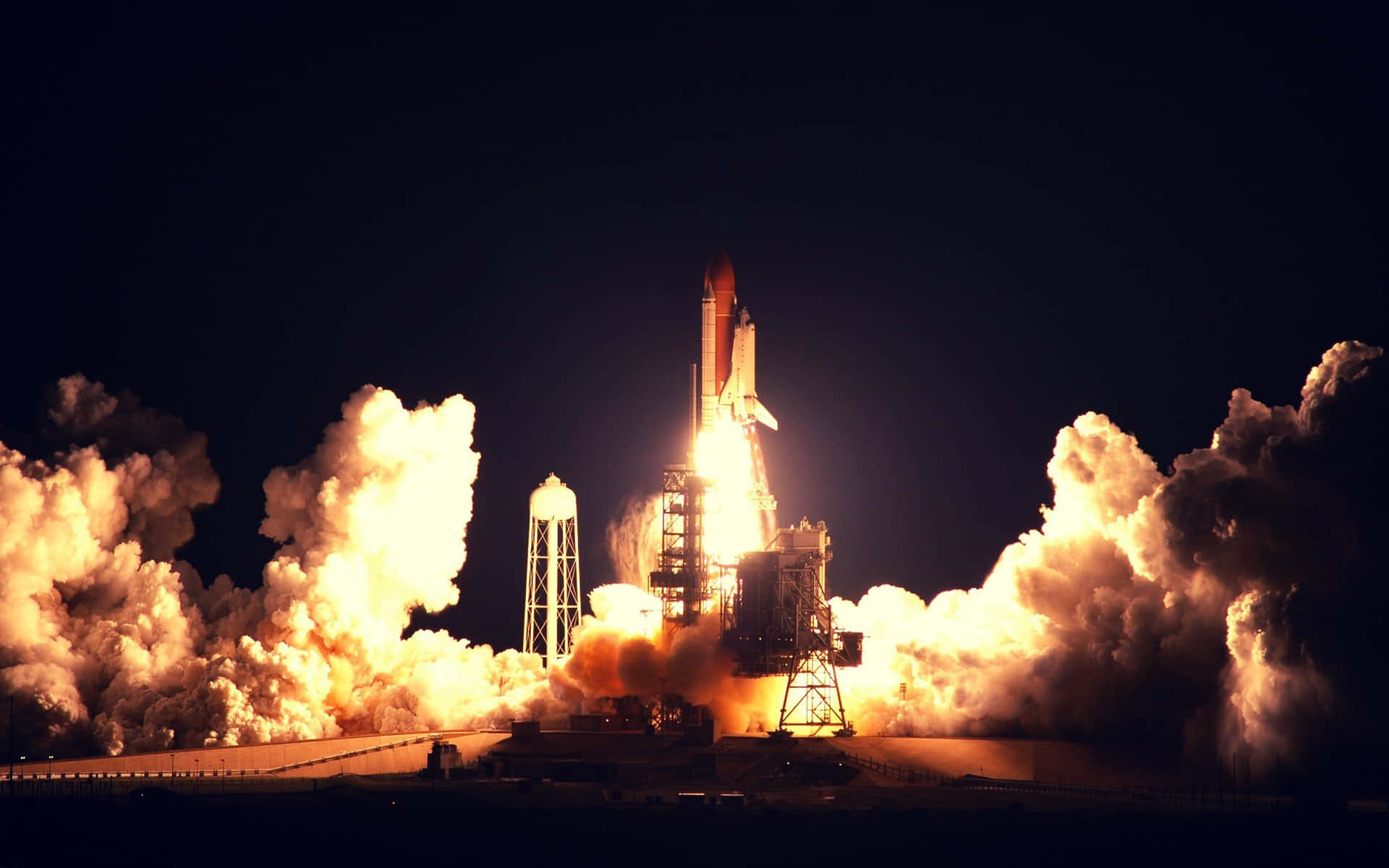 NASA 動態圖片 桌布 壁紙 — 一架太空梭在發射時，以熾熱的推力和滾滾濃煙點燃，映襯著漆黑的夜空。