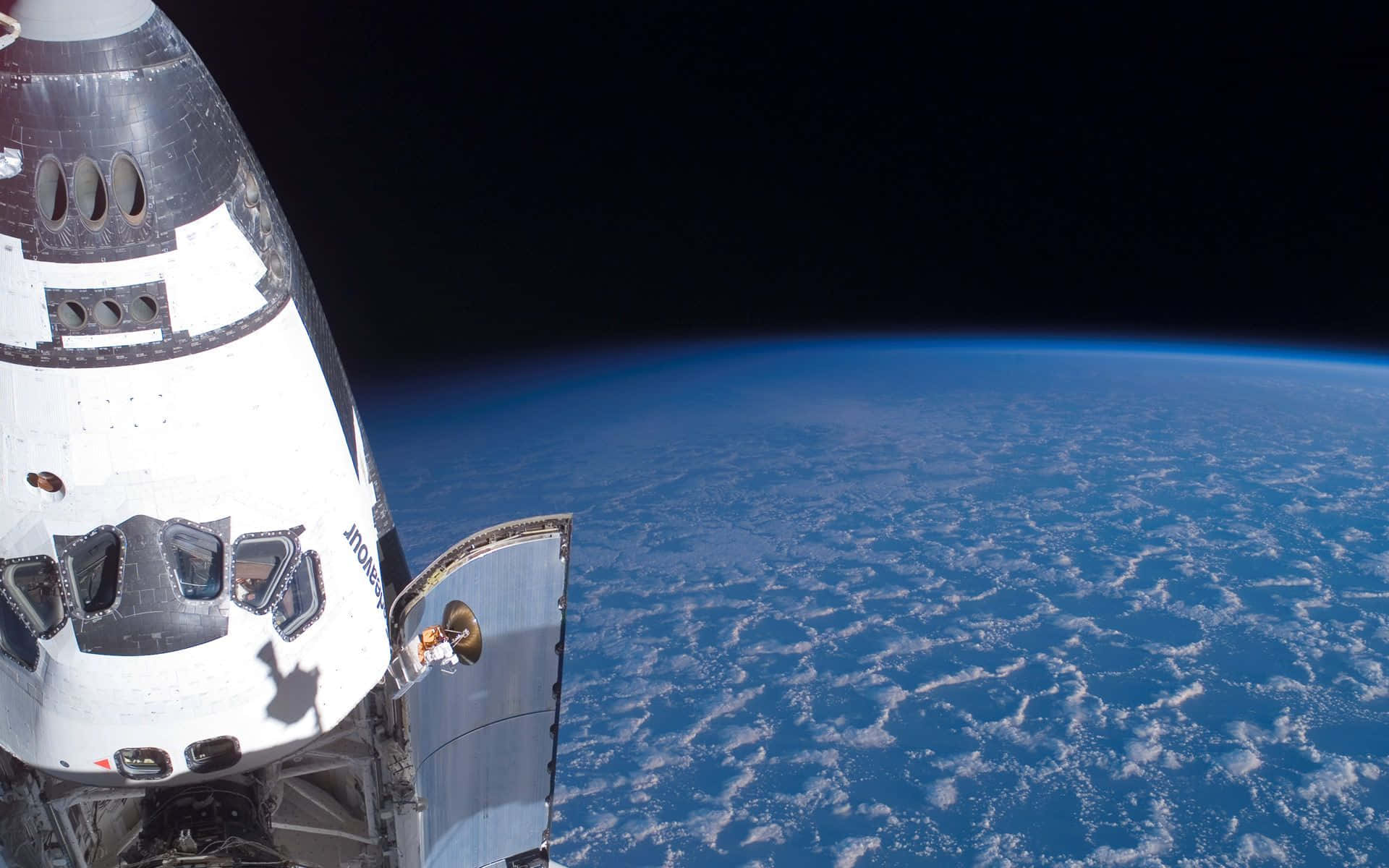 space shuttle 桌布 壁紙 — 一架太空梭懸浮在地球彎曲的藍色地平線上方，點綴著白色雲朵。
