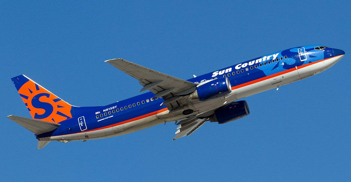 flying 桌布 壁紙 — 一架太陽鄉村航空的波音737以其鮮豔的藍色和橙色塗裝在清澈的藍天中翱翔。