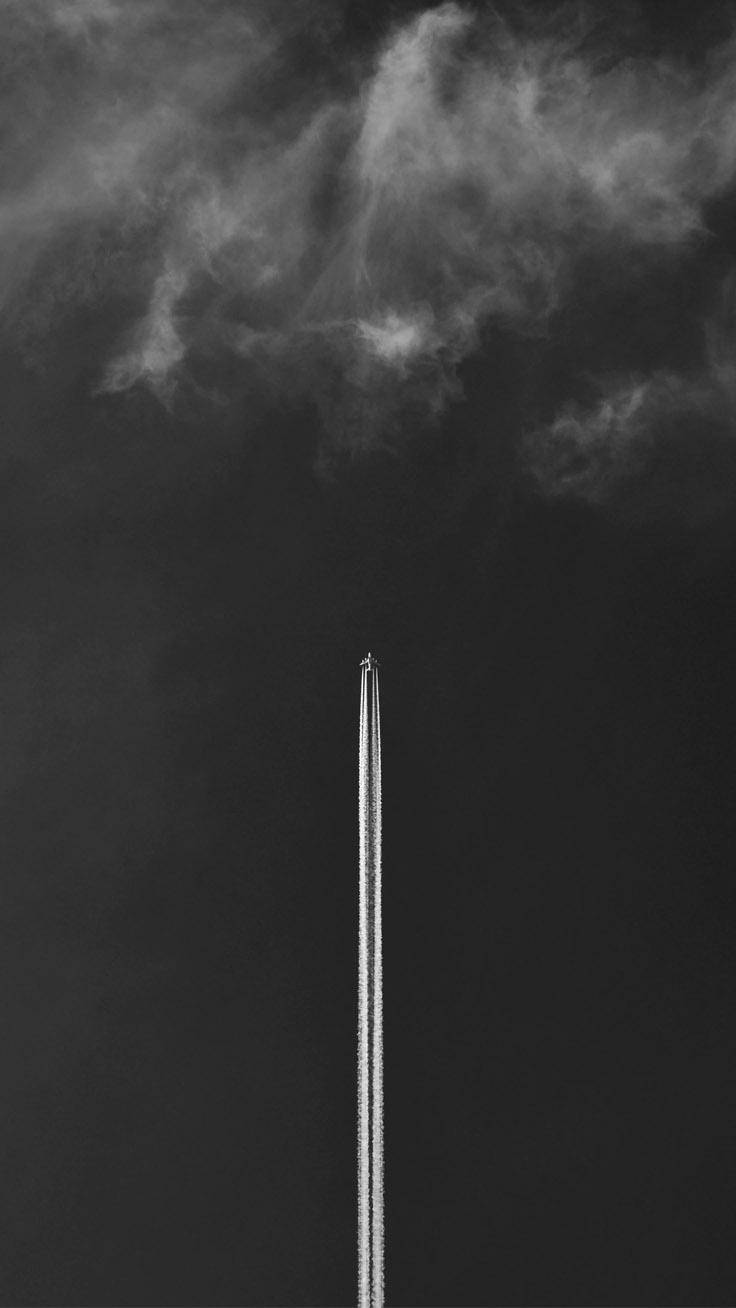 iPhone 桌布 壁紙 — 一架孤獨的飛機在單色的戲劇性多雲天空中留下一條長長的凝結尾跡。
