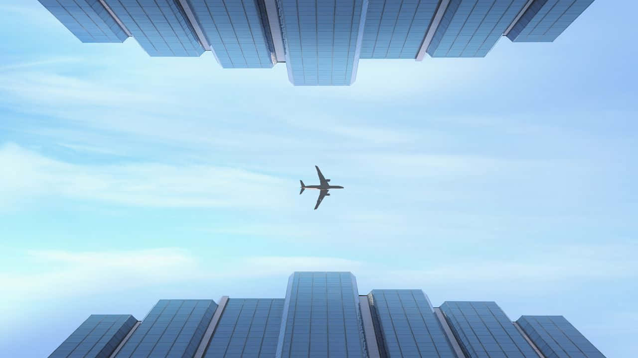 720p Plane 桌布 壁紙 — 一架孤獨的飛機在淡藍色天空和薄雲下，飛翔於高聳的玻璃摩天大樓之間。
