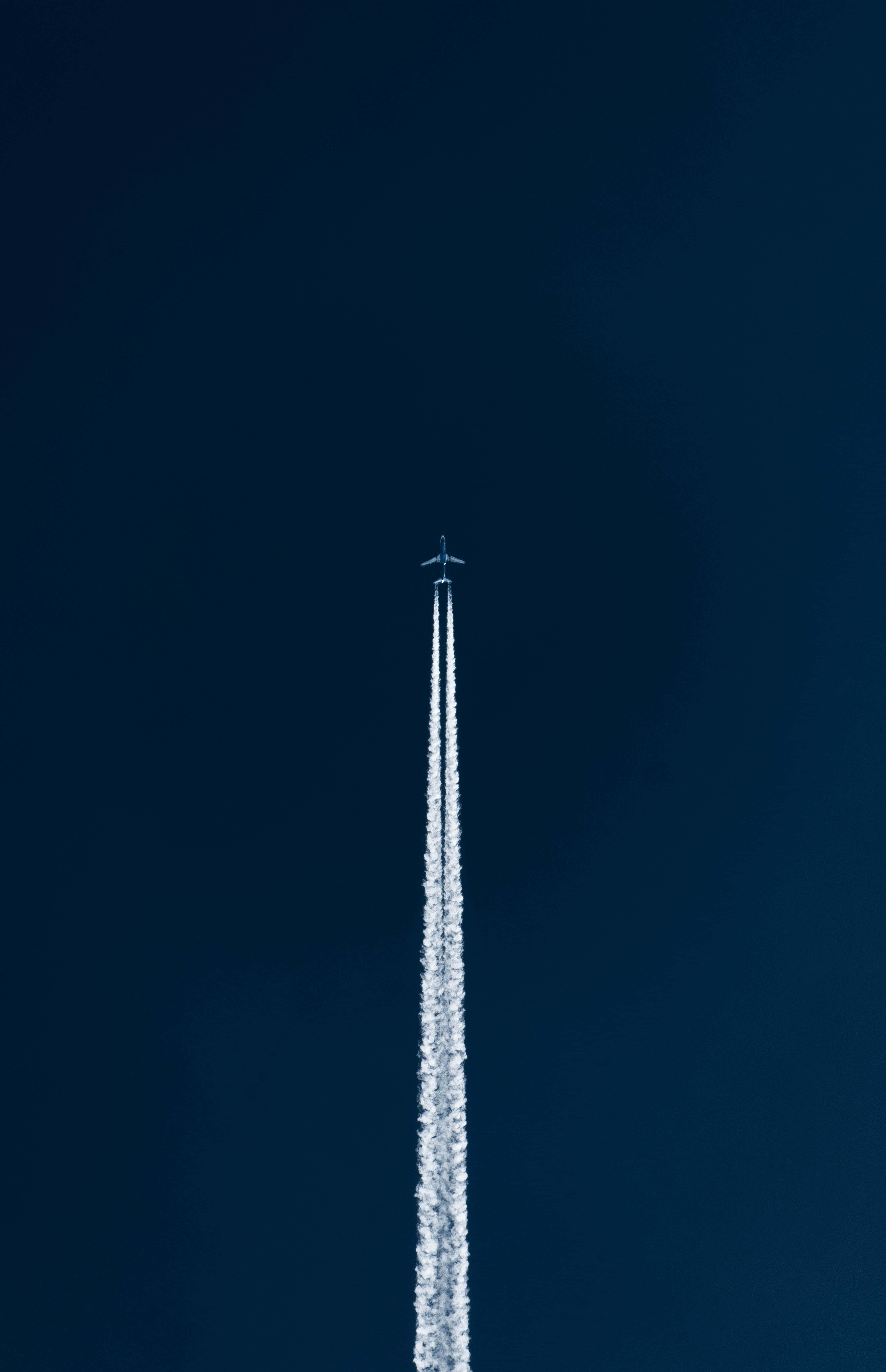 Jet 桌布 壁紙 — 一架孤獨的飛機在深藍色的天空中垂直上升，留下一道長長的白煙。