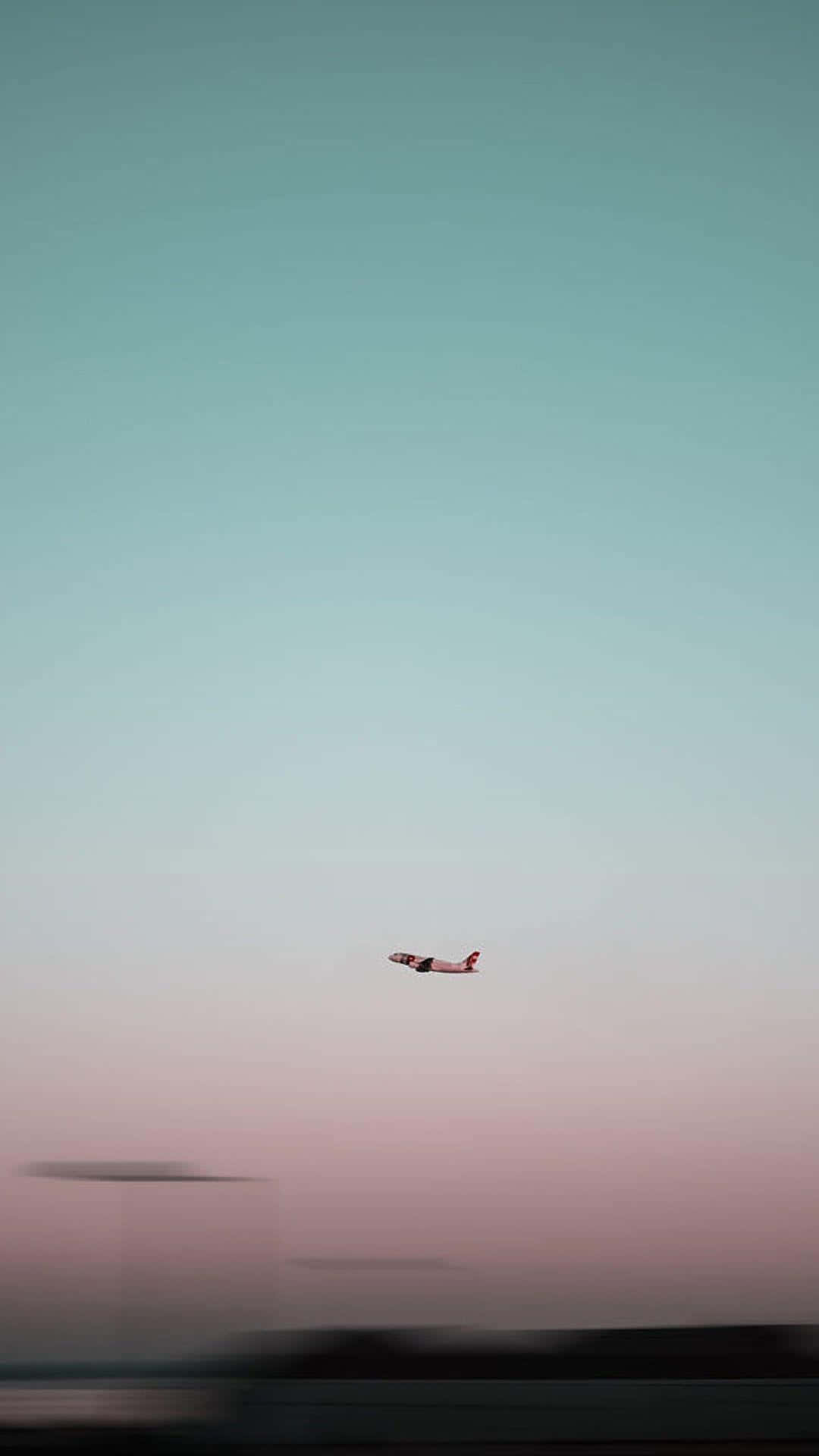 Travel Aesthetic Phone 桌布 壁紙 — 一架孤獨的飛機在黃昏時分滑過從青綠色漸變到粉紅色的天空。