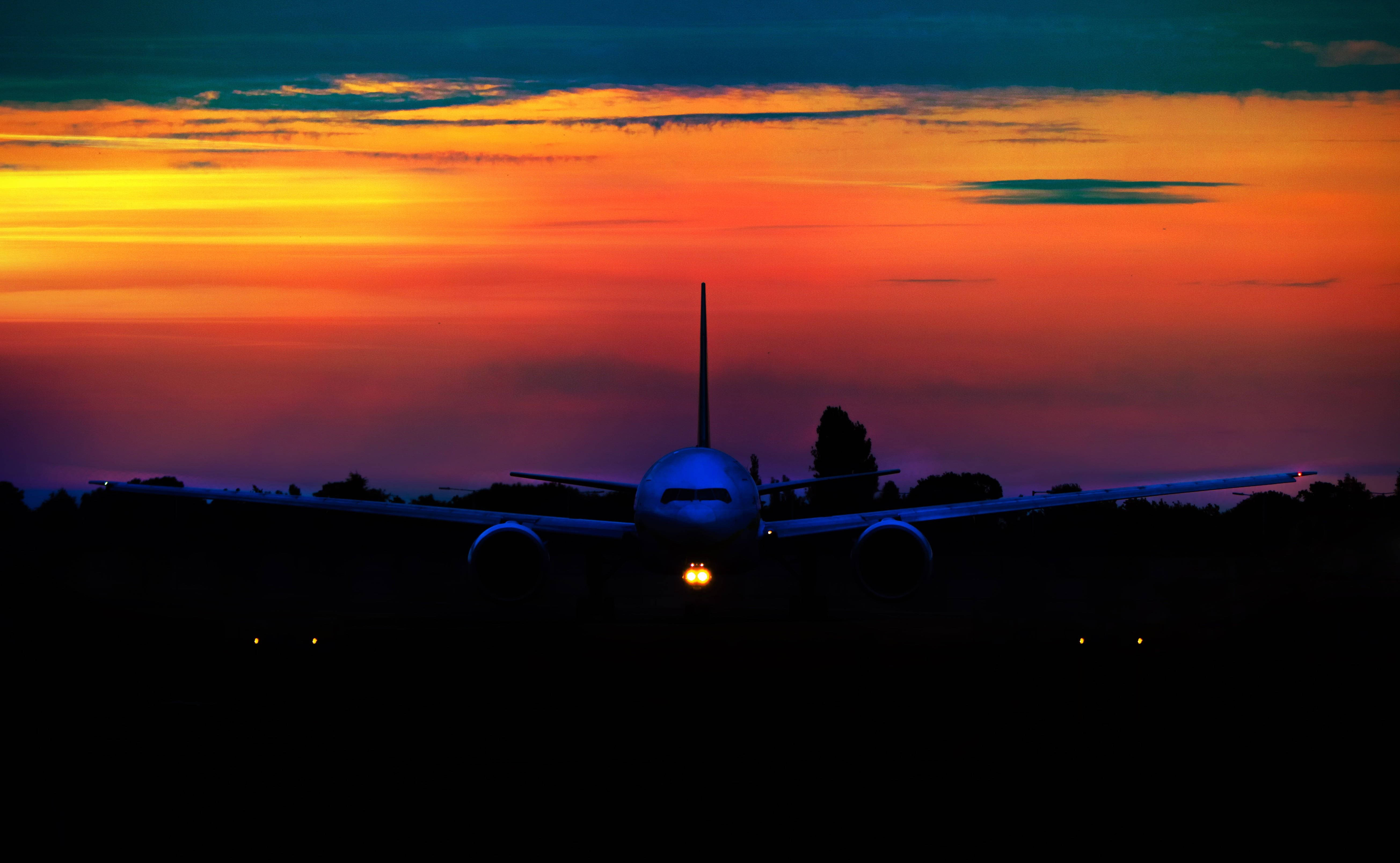 Silhouette 桌布 壁紙 — 一架客機在火紅的日落天空襯托下形成剪影，駕駛艙燈光閃爍。