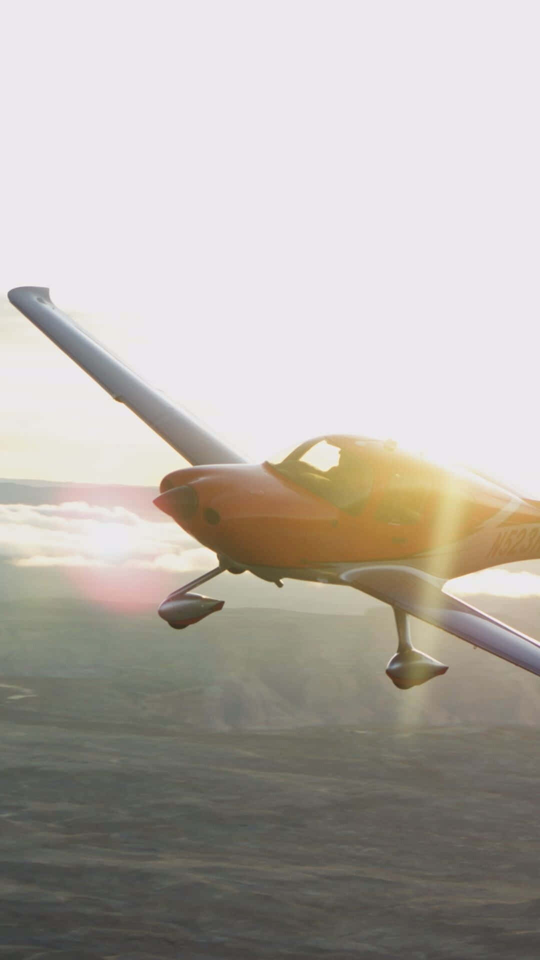Aircraft 桌布 壁紙 — 一架小型橙色飛機在金色夕陽光芒中翱翔，飛越霧氣瀰漫的山區地形。