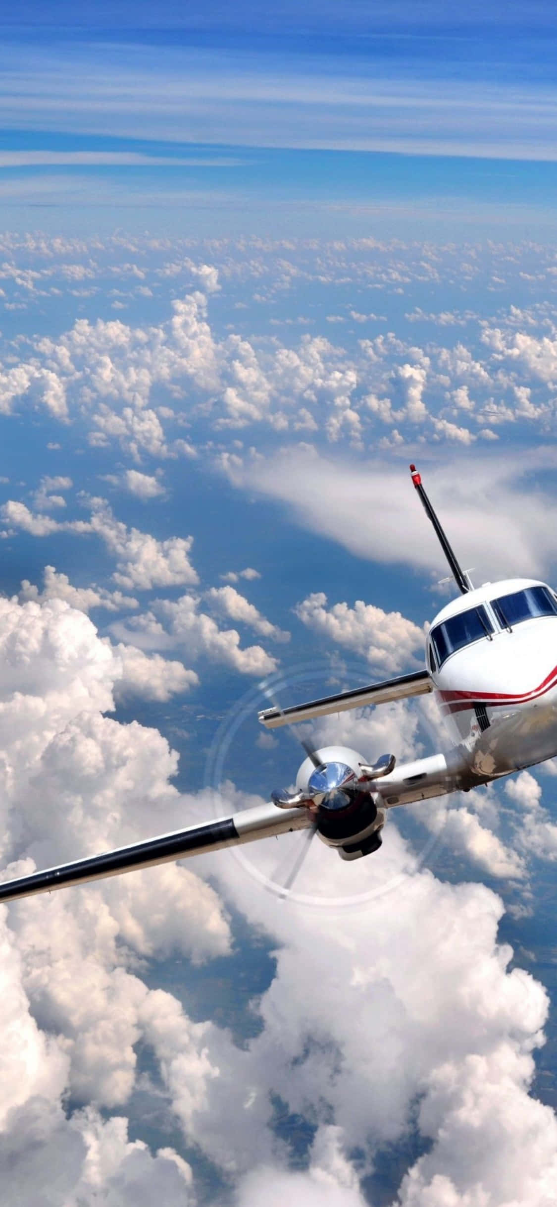 iPhone Xs Microsoft Flight Simulator 桌布 壁紙 — 一架小型螺旋槳飛機在晴朗藍天下翱翔於蓬鬆白雲之上。