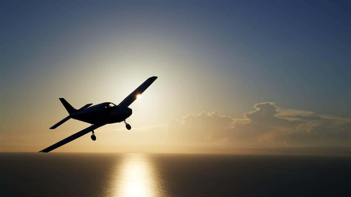 Aviation 桌布 壁紙 — 一架小型飛機在平靜海洋上空，襯著柔和雲朵和燦爛夕陽的剪影。