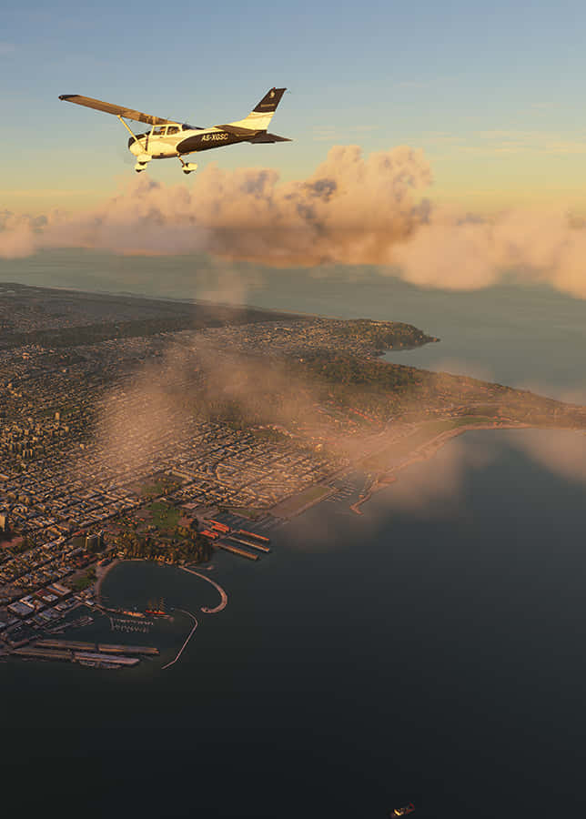 Android Microsoft Flight Simulator 桌布 壁紙 — 一架小型飛機在黃金時刻翱翔於沿海城市上空，下方有雲層，海洋延伸至地平線。