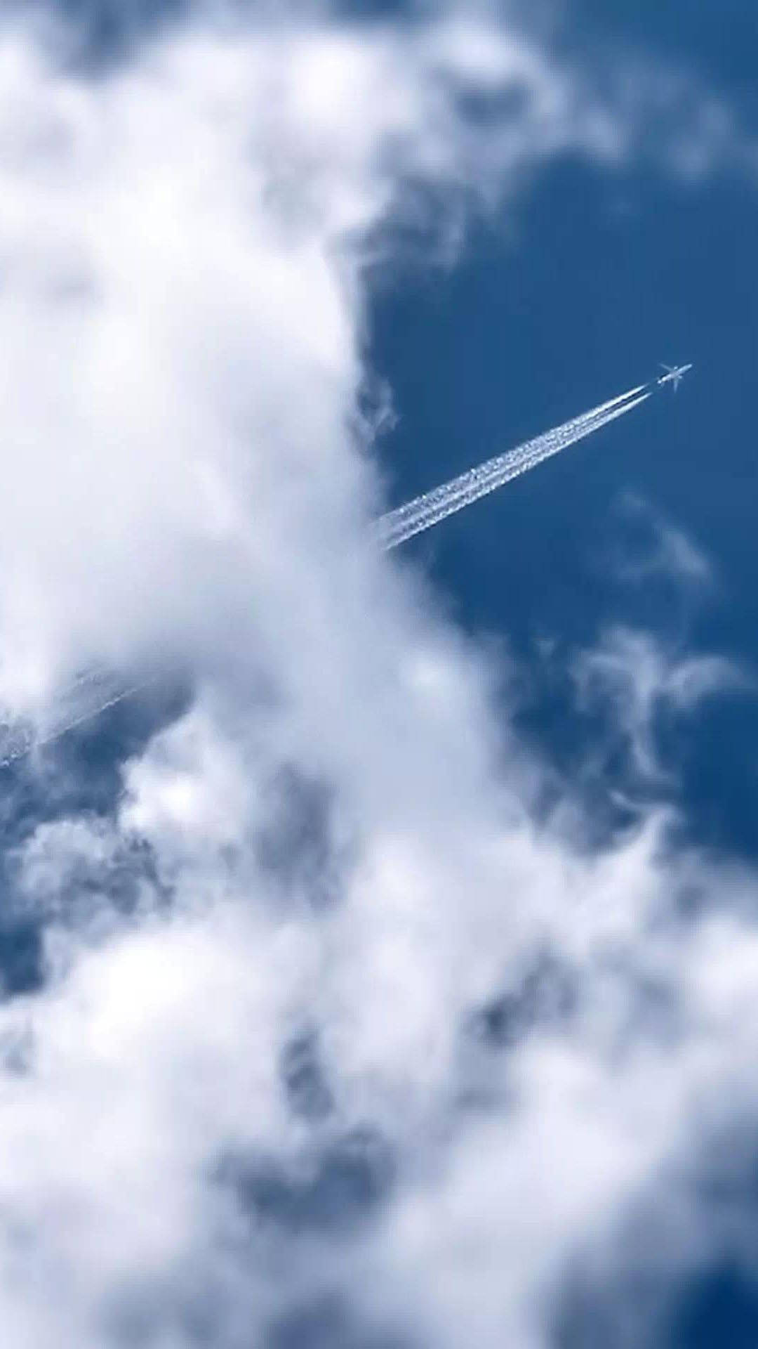 飛機 桌布 壁紙 — 一架小型飛機留下兩條清晰的凝結尾跡，劃過被蓬鬆白雲部分遮蔽的鮮豔藍天。