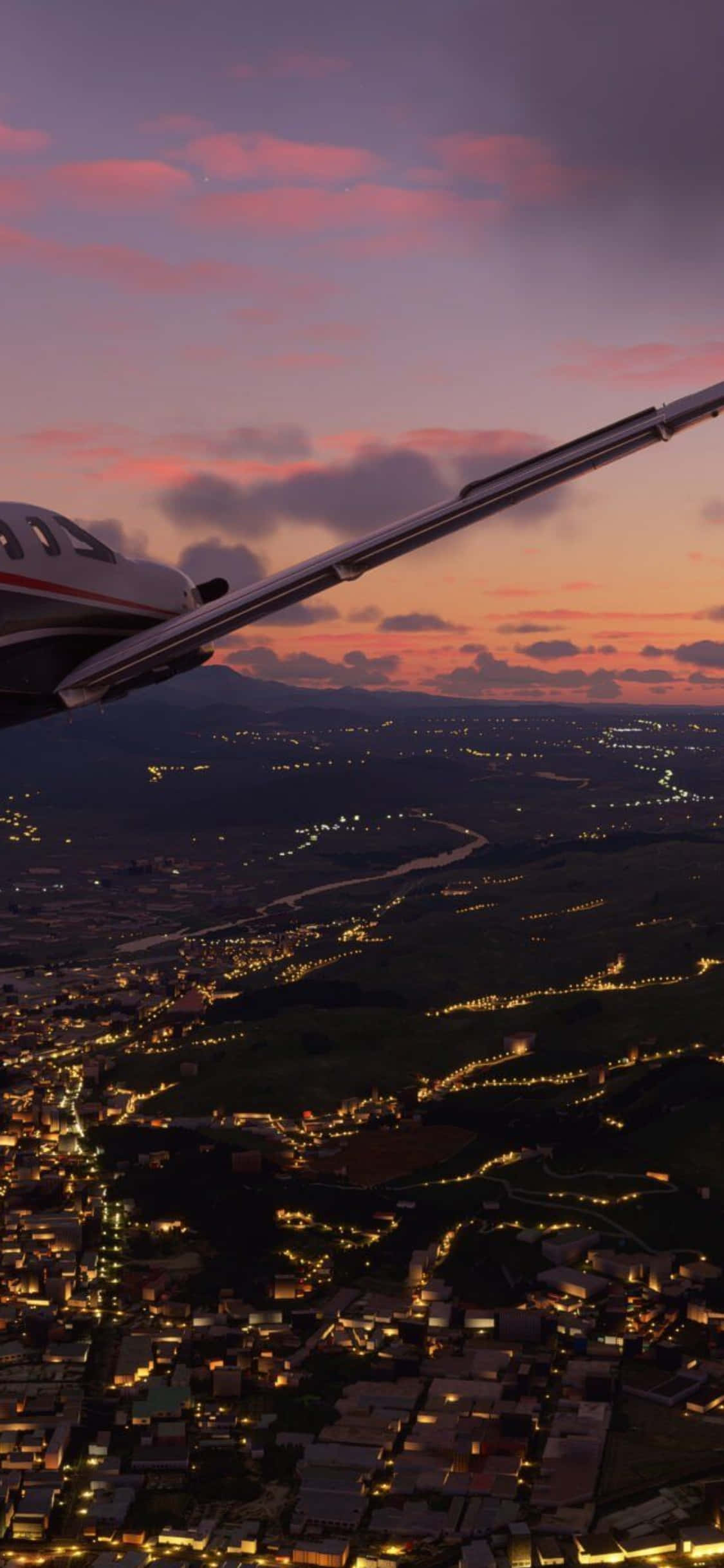 iPhone Xs Microsoft Flight Simulator 桌布 壁紙 — 一架小型飛機的機翼在黃昏時分滑翔過廣闊的城市景觀，溫暖的燈光在下方閃爍，映襯著粉紅和紫色的天空。