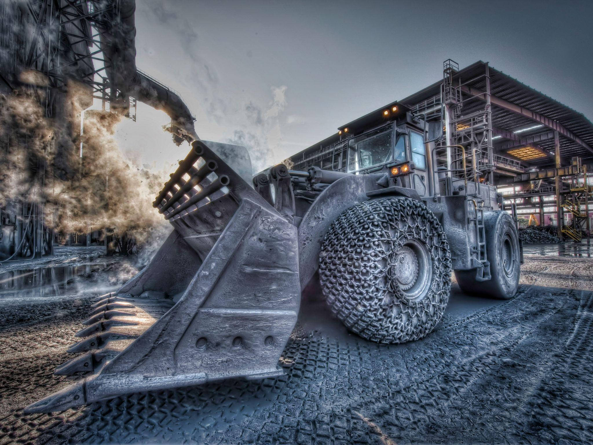 construction 桌布 壁紙 — 一架巨大的工業輪式裝載機主宰著一個骯髒的鋼鐵廠，在陰沉的暮色天空下，機械冒出的煙霧裊裊升起。
