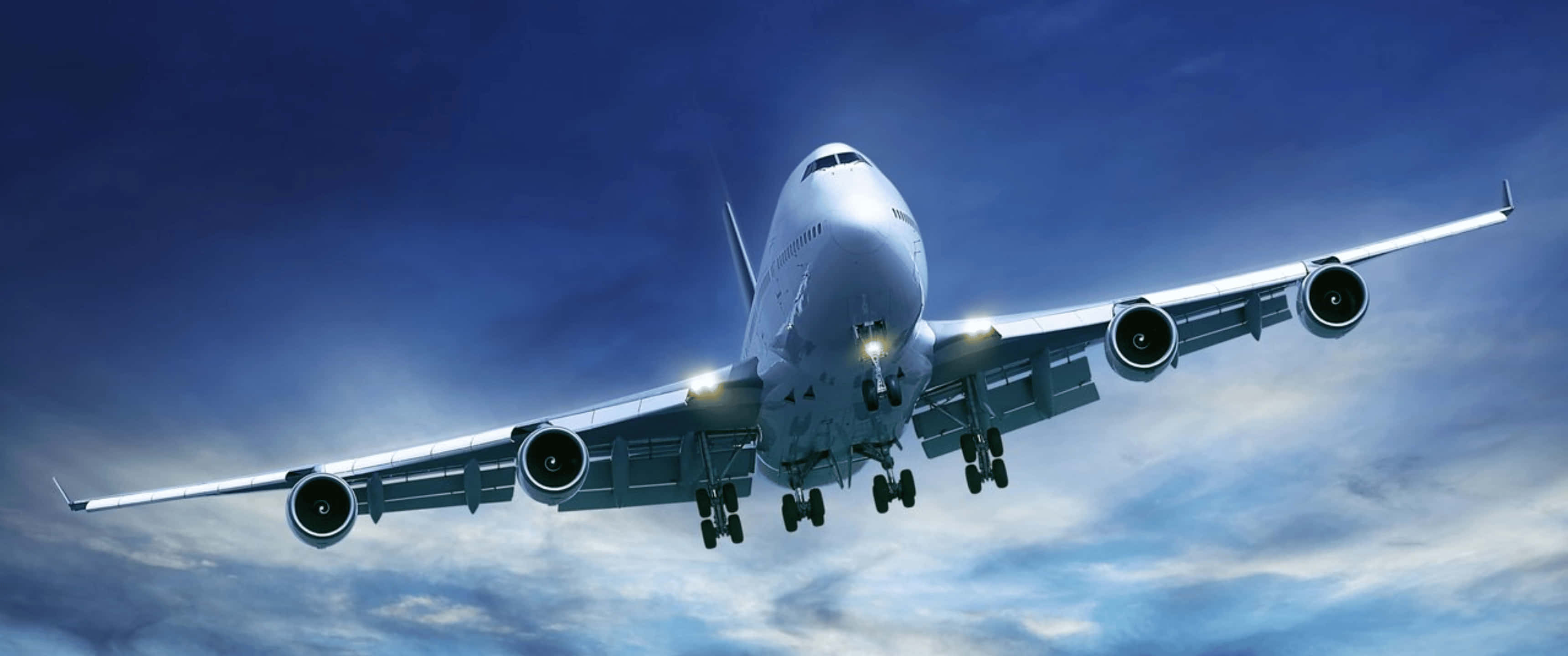 Plane 桌布 壁紙 — 一架巨大的白色珍寶客機放下起落架，在戲劇性的藍天和散落的雲朵中下降。