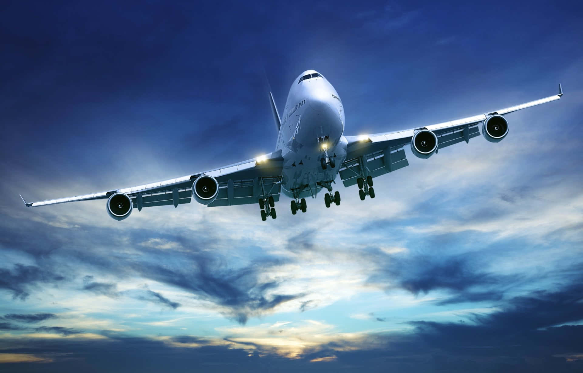 Plane 桌布 壁紙 — 一架巨大的白色珍寶客機放下起落架，在佈滿藍色和金色雲彩的戲劇性暮色天空中下降。