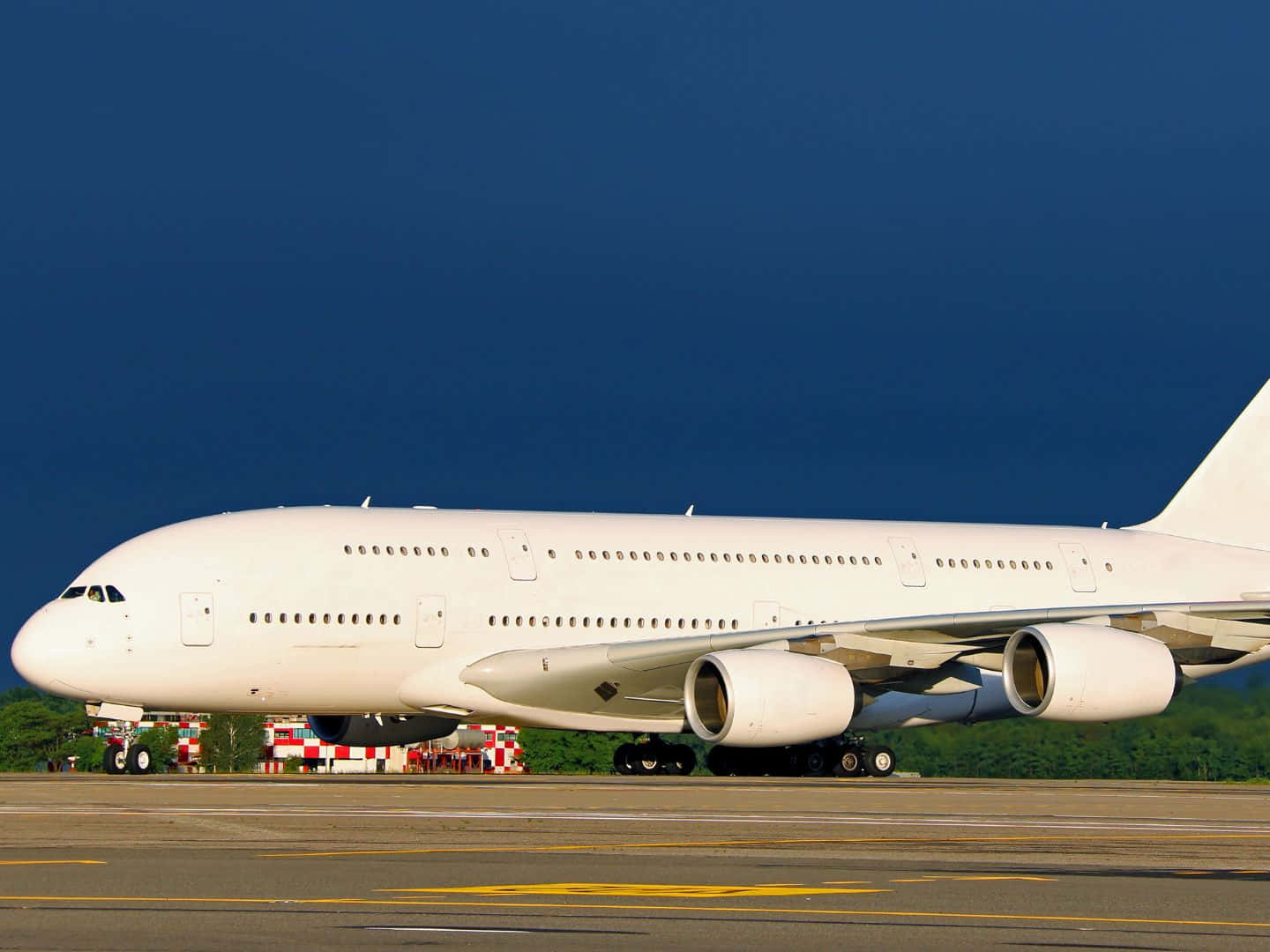 Aircraft 桌布 壁紙 — 一架巨大的白色空中巴士A380飛機停在跑道上，背景是深藍色的天空和綠樹。
