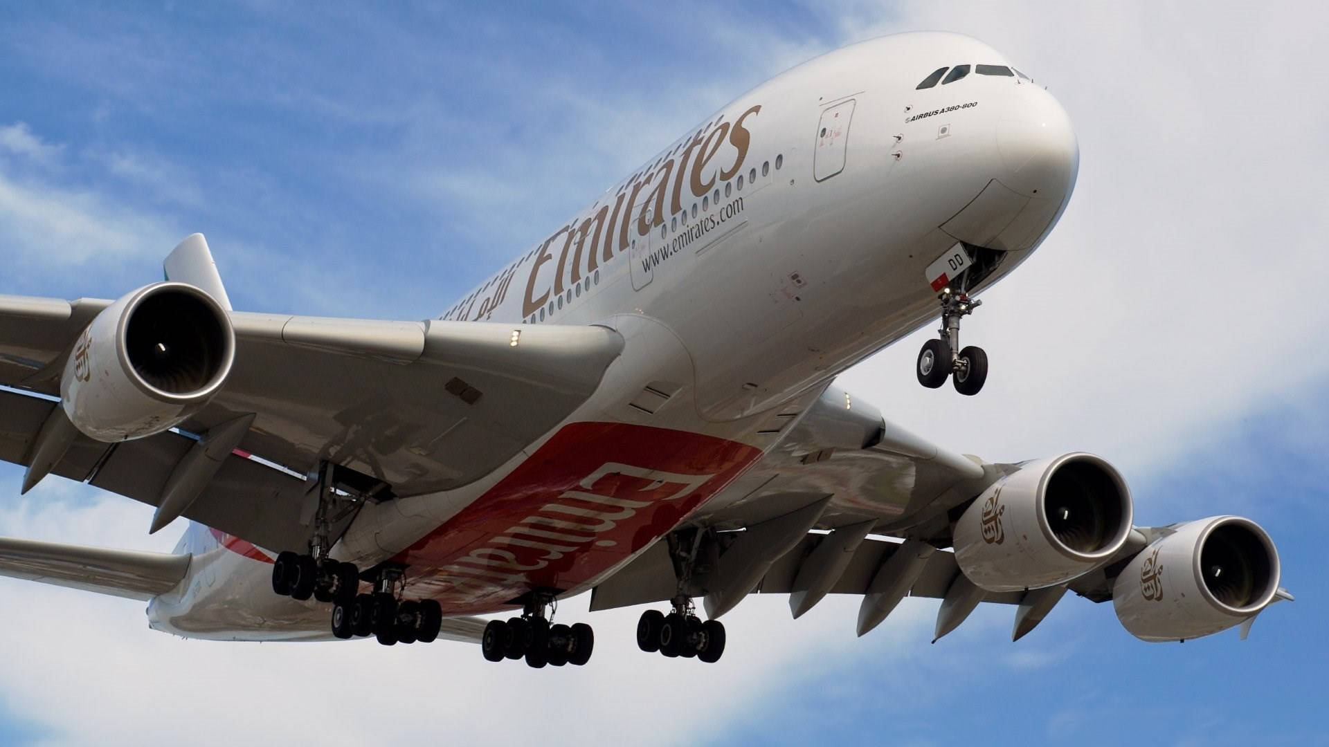 飛機 桌布 壁紙 — 一架巨大的阿聯酋航空空中巴士A380正在降落，起落架放下，背景是明亮的藍天和零星的白雲。