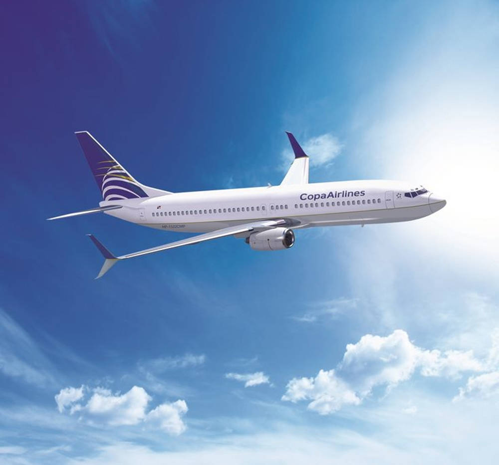  壁紙 — 一架巴拿馬航空客機優雅地翱翔於點綴著蓬鬆白雲的明亮藍天中。